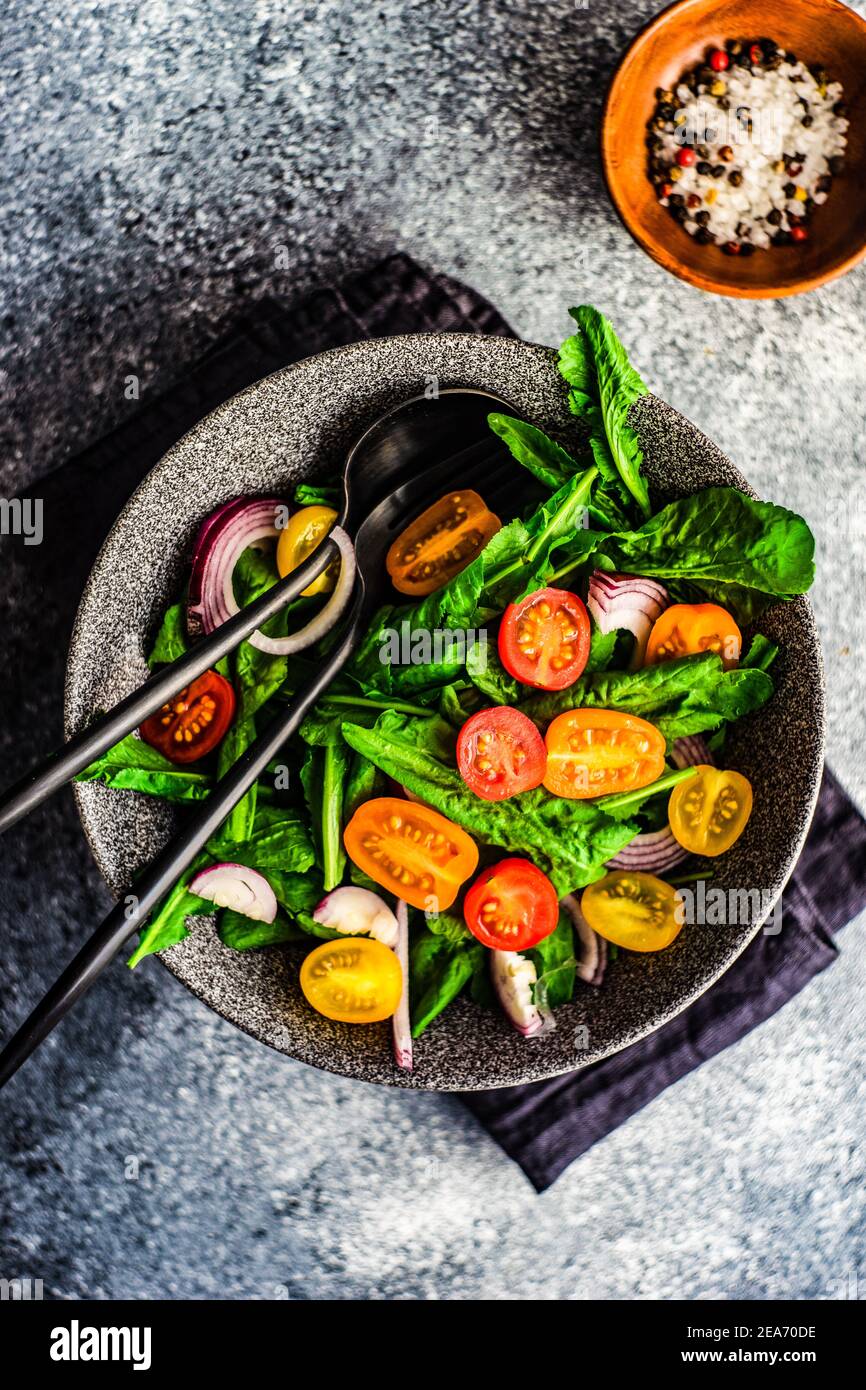 Ciotola di insalata di razzo fresca con pomodori ciliegini e rosso cipolla Foto Stock