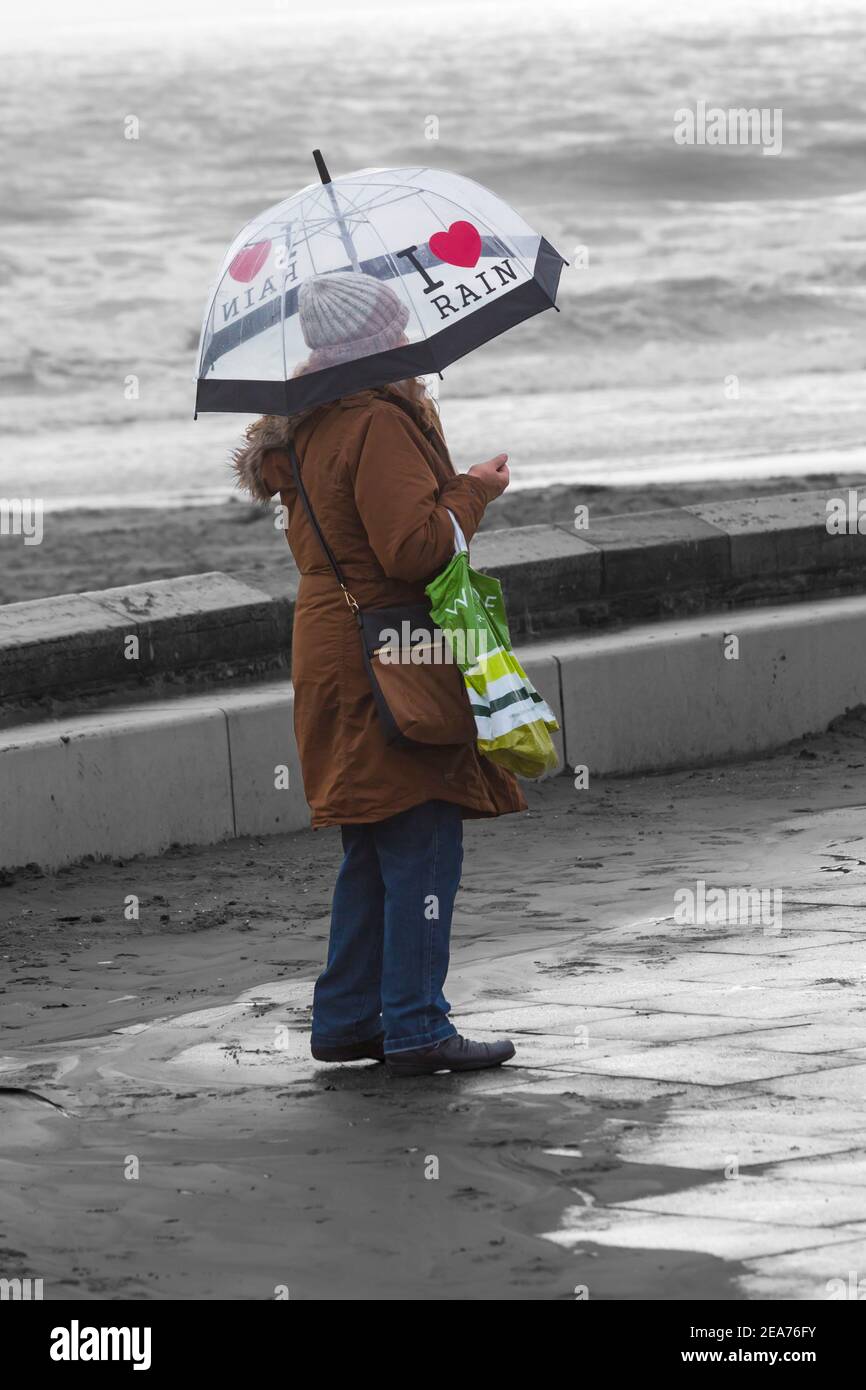 Donna che ripara sotto i love Rain ombrello a Bournemouth, Dorset UK nel mese di dicembre Foto Stock