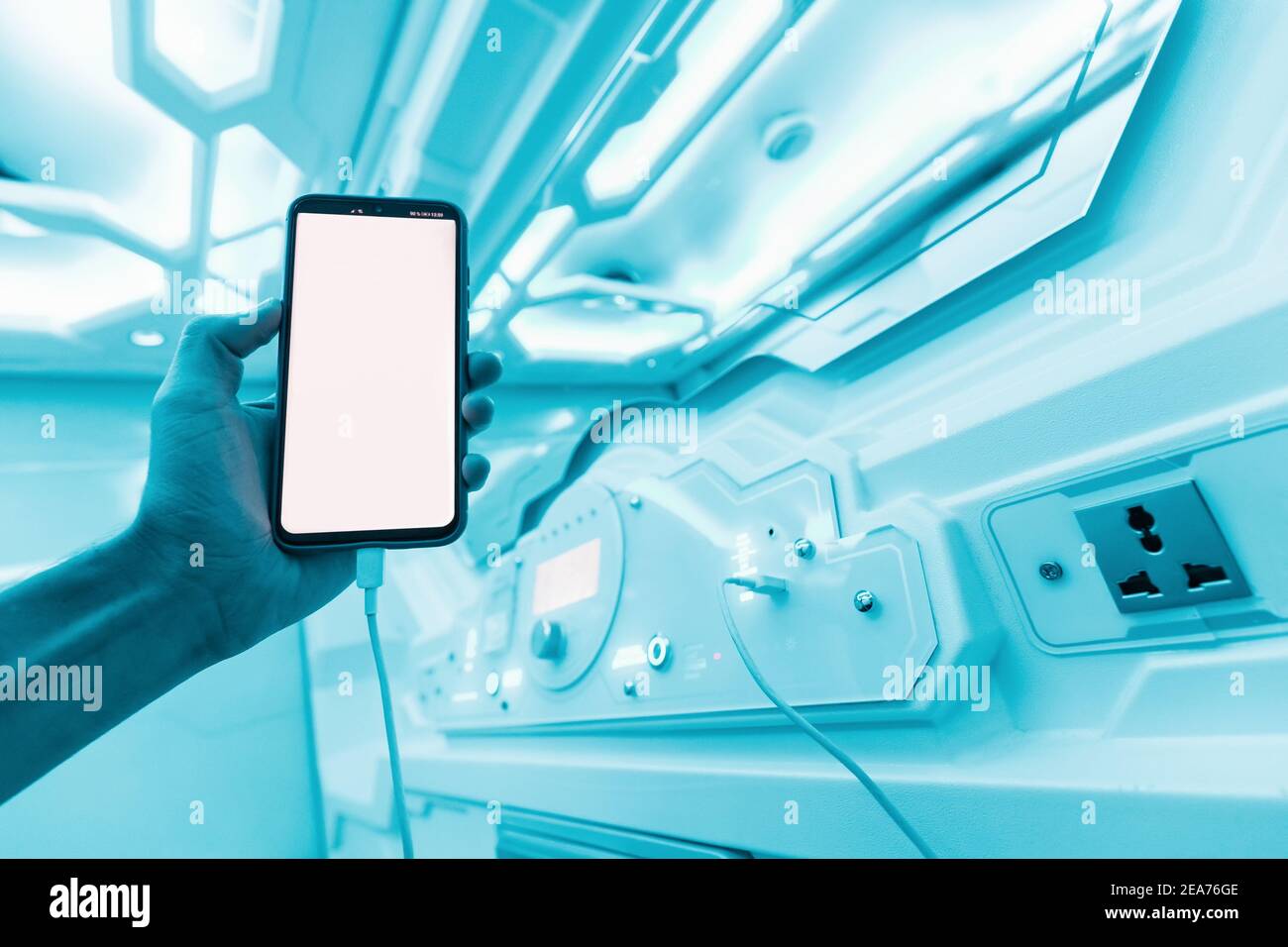 L'uomo riposa in un albergo a capsule e legge le notizie sui social network prima di andare a letto. Interni della navicella spaziale sci-fi in colori neon e UV Foto Stock
