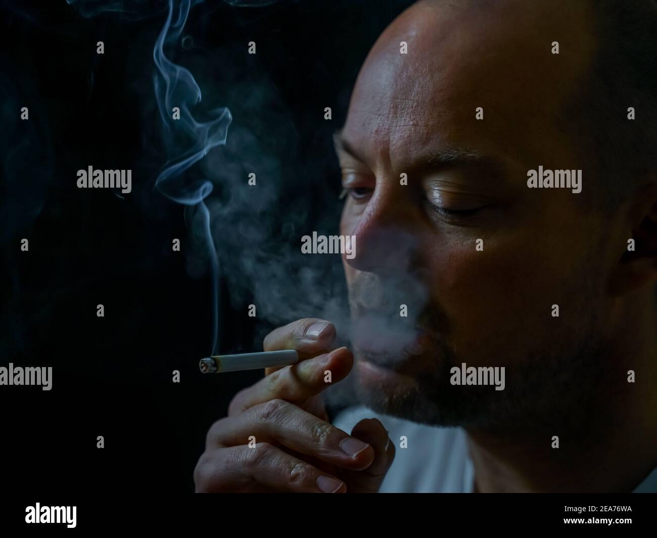 Uomo che fuma una sigaretta che emette fumo bianco. Foto Stock