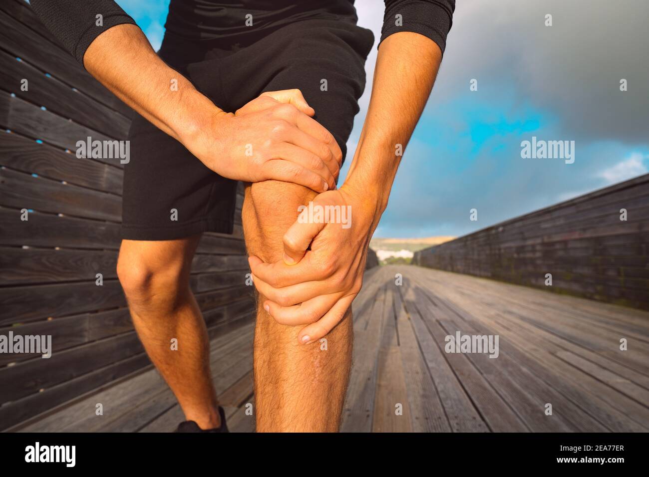 Uomo runner che tiene il ginocchio doloroso a causa di una lesione. Lesioni da allenamento e esercizio fisico Foto Stock