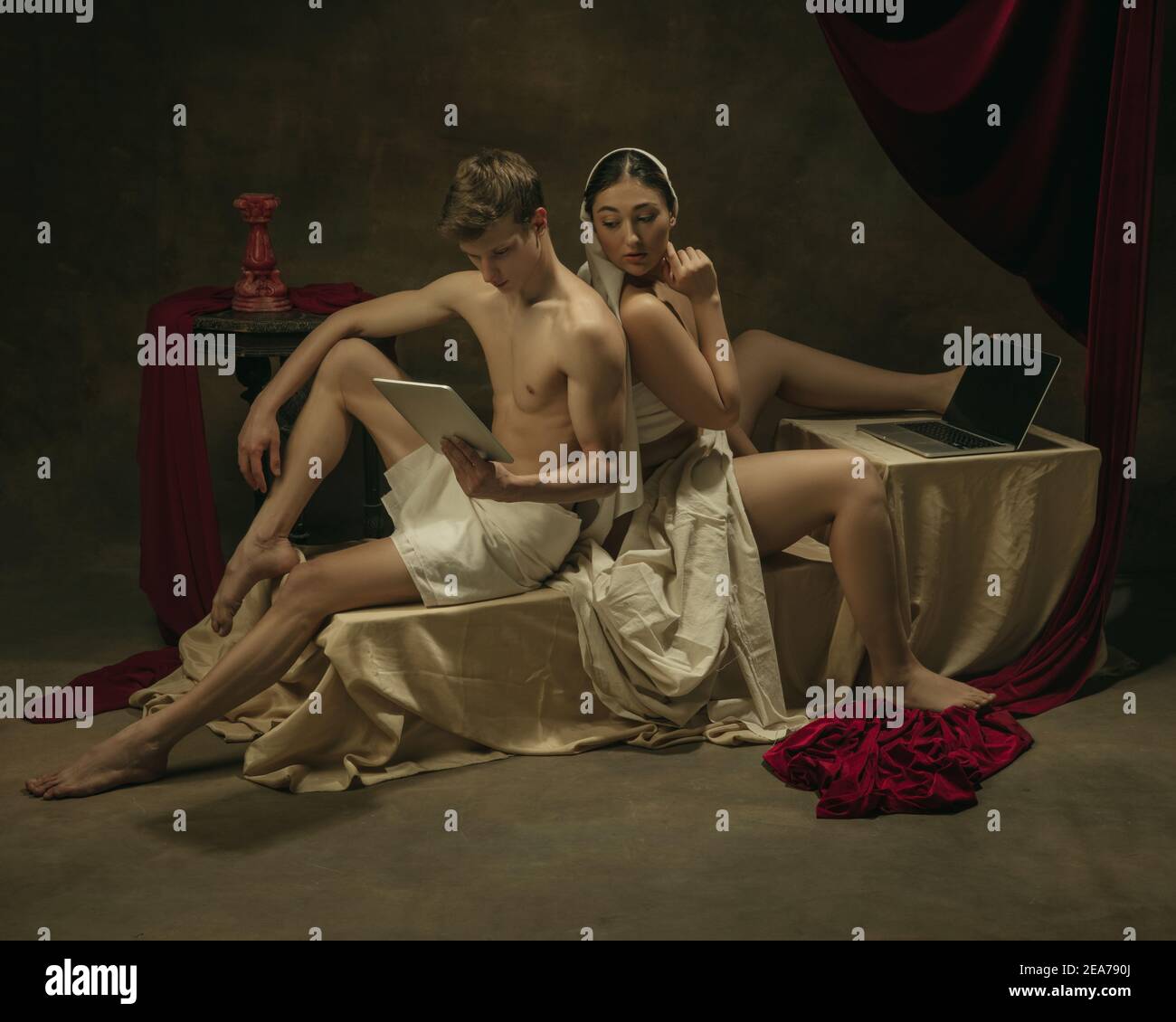 Peeking di che cosa l'uomo fa. Rifacimento moderno di opere d'arte classiche a tema tecnologico moderno - giovane coppia medievale su sfondo scuro, color oro. Concetto di tecnologie, dispositivi, comunicazione, pubblicità. Foto Stock