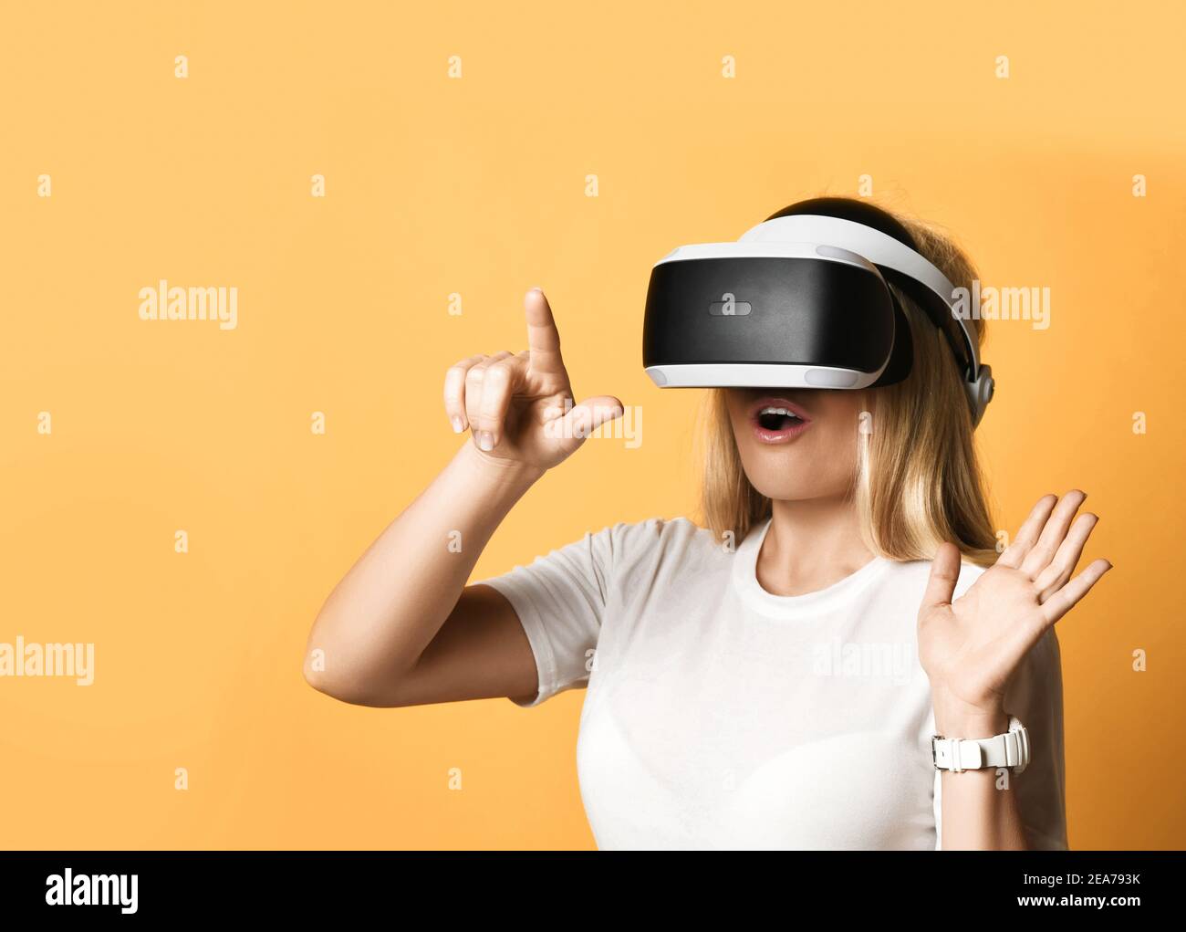 Ritratto di donna in una t-shirt bianca con occhiali VR esplorando realtà aumentata premendo il tasto virtuale con le dita Foto Stock