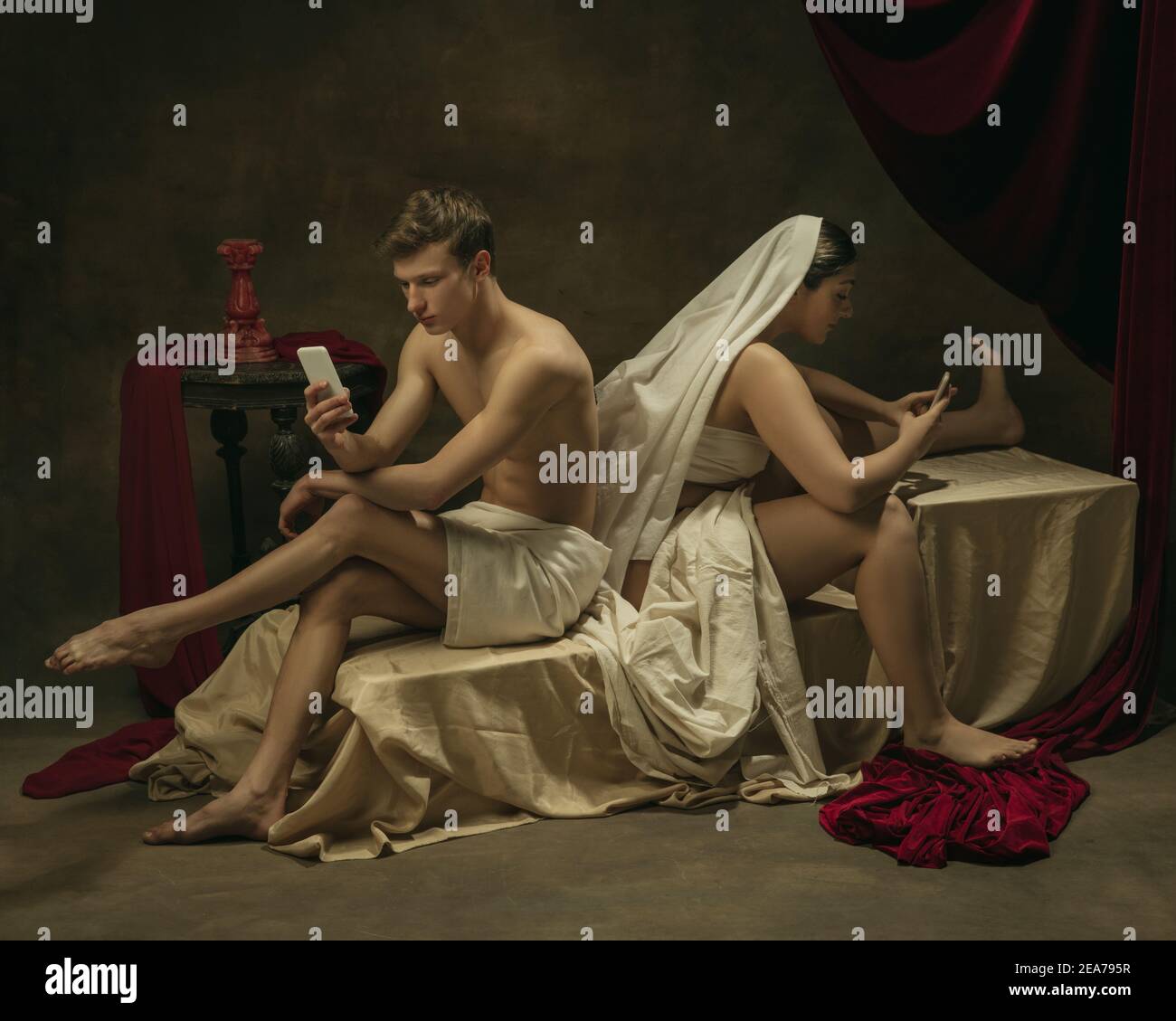 Chat tramite cellulare. Rifacimento moderno di opere d'arte classiche a tema tecnologico moderno - giovane coppia medievale su sfondo scuro, color oro. Concetto di tecnologie, dispositivi, comunicazione, pubblicità. Foto Stock