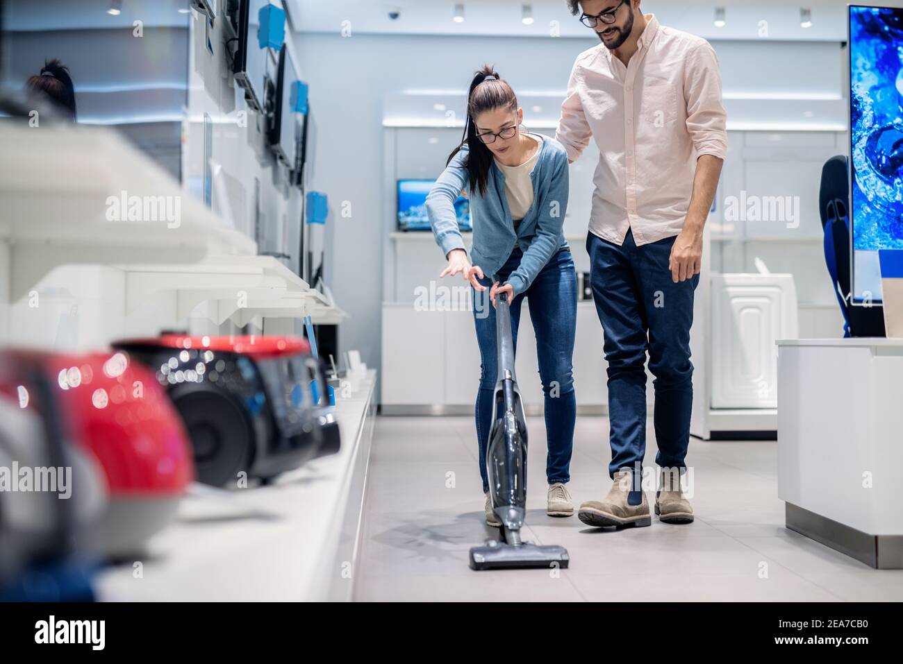 Donna che prova l'aspirapolvere nel negozio di tecnologia. Concetto di nuove tecnologie. Foto Stock