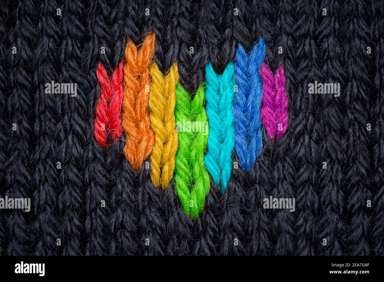 Cuore colorato lavorato a maglia fatto di filato su sfondo nero. Foto Stock