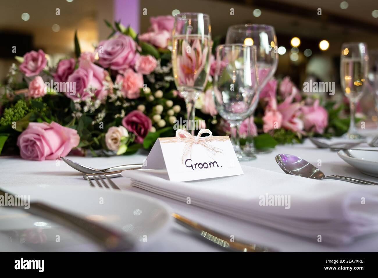 Ambiente per la colazione di nozze con il biglietto d'auguri in cima tavolo in attesa di arrivo con sposa e rose rosa e. bicchieri scintillanti di champagne Foto Stock