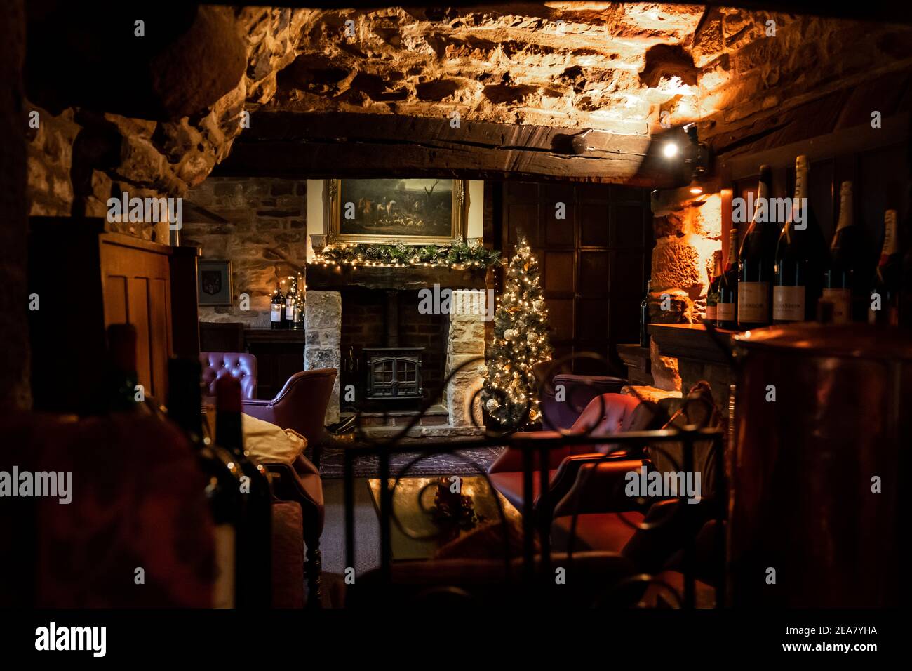 Tradizionale accogliente pub inglese vecchio accogliente sala da bere sedie in pelle Con pareti in pietra e travi in legno durante le feste albero di Natale Foto Stock