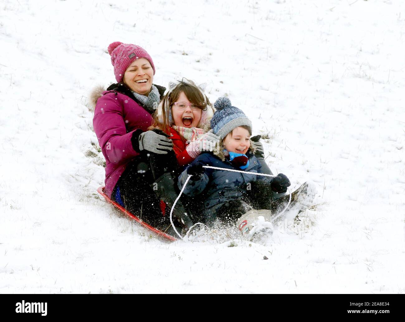 Haverhill, Suffolk, Regno Unito. 8 febbraio 2021. Elizabeth Mitchell con i bambini Ivy 5 e Albert 3 si divertono a slittare dopo la pesante nevicata. Credit: Headlinephoto/Alamy Live News. Foto Stock