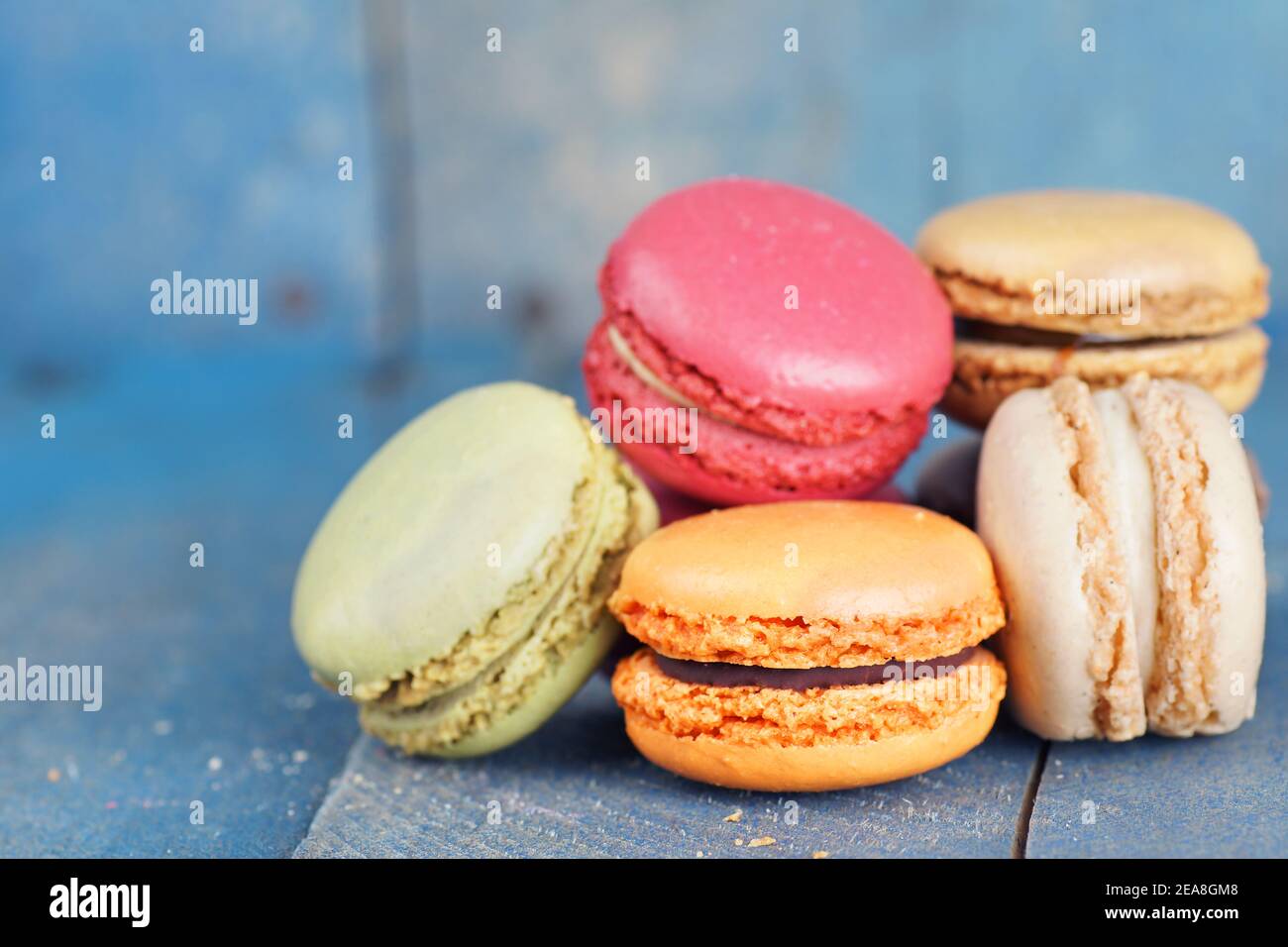 Macaron francesi colorati su vecchio sfondo di tavole di legno blu Foto Stock