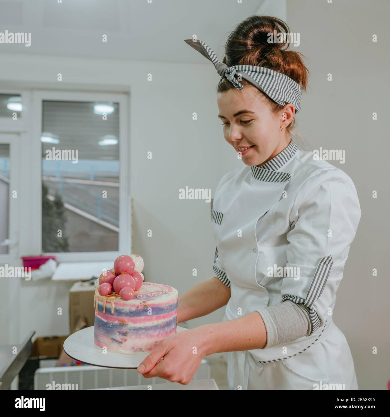 Donna confectioner che tiene la torta di compleanno colorata con le palle di  cioccolato dentro la pasticceria studio Foto stock - Alamy