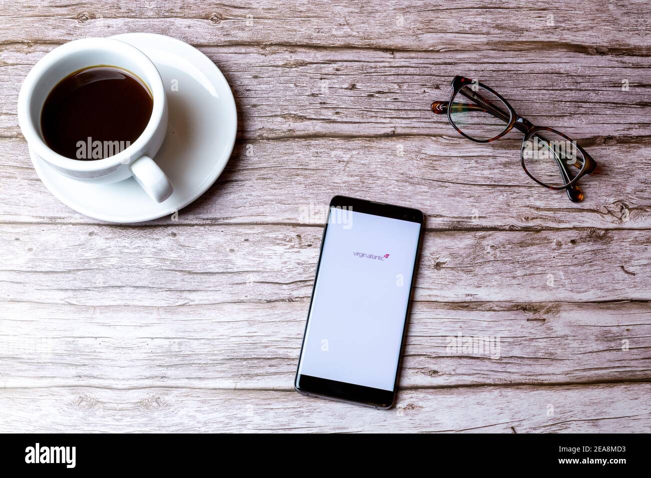 Un telefono cellulare o un telefono cellulare posato su un legno Tavolo con l'app Virgin atlantic aperta accanto a a. caffè Foto Stock