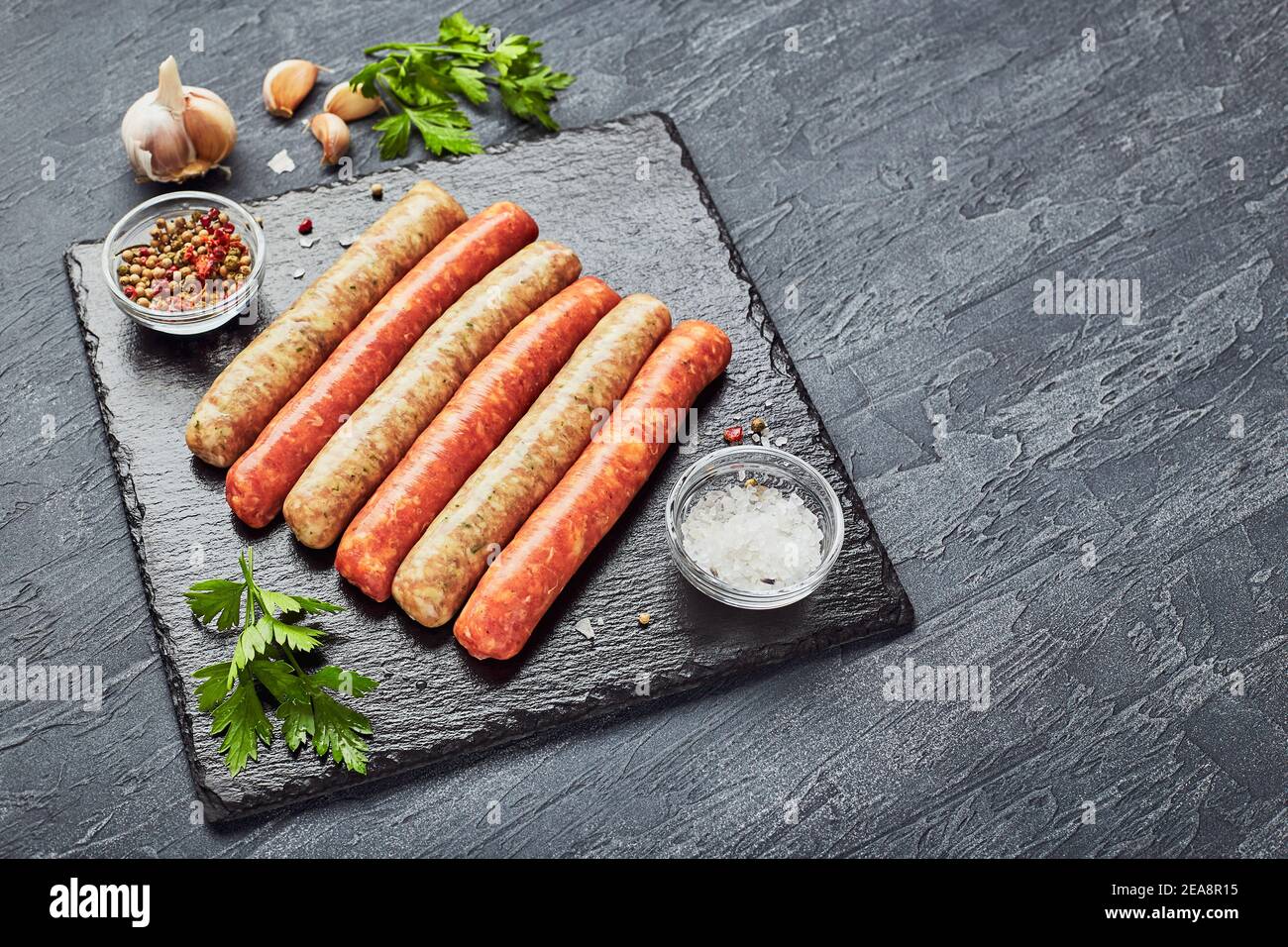 Macellai crudi salsicce su ardesia con erbe. Vista dall'alto. Foto Stock