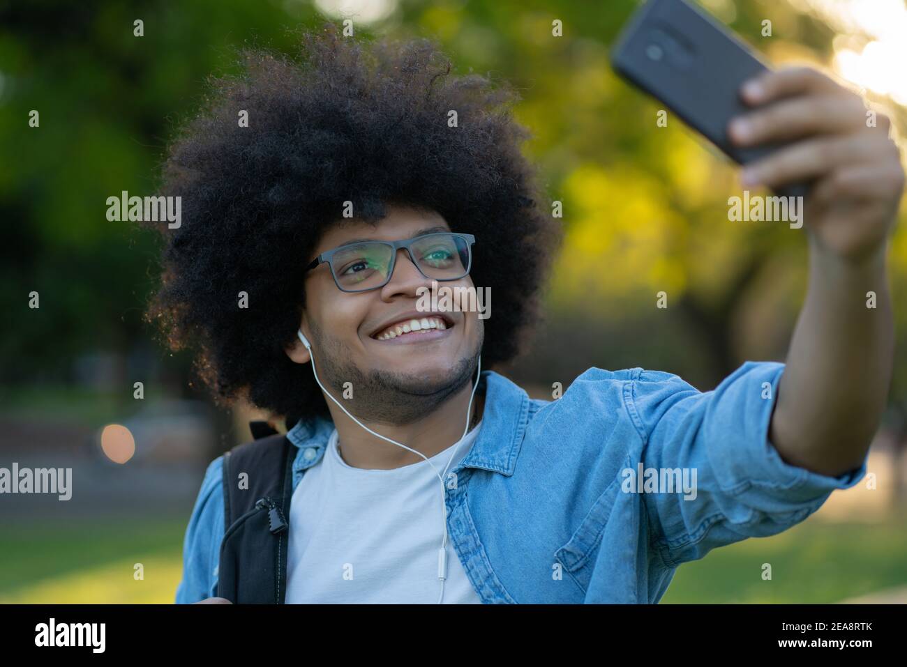 Uomo latino che prende un selfie con il telefono all'aperto. Foto Stock