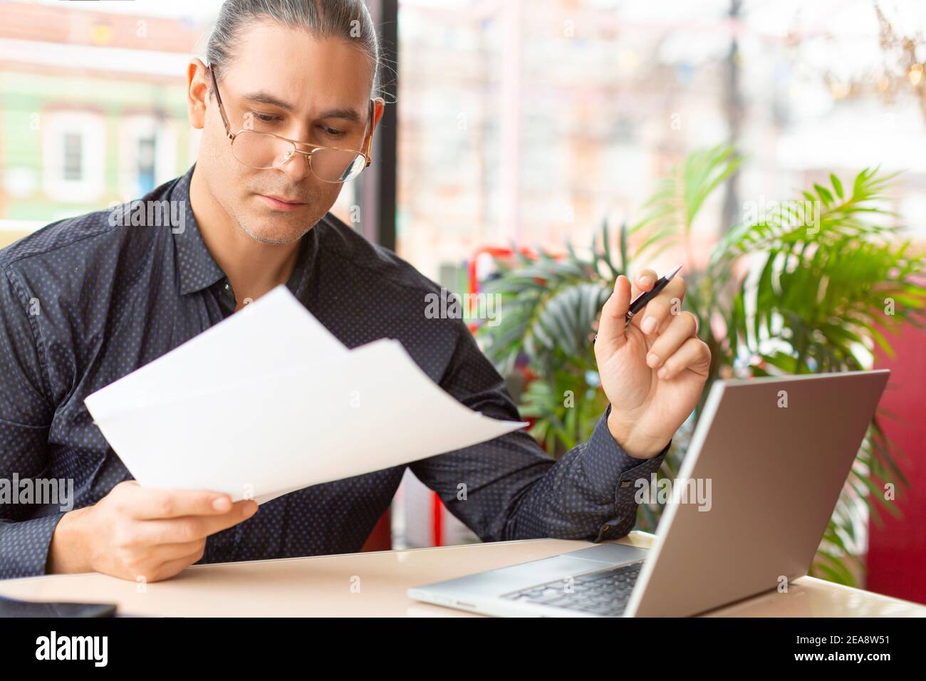 Uomo d'affari lavora con documenti davanti al computer portatile. Concetto di lavoro online a distanza. Foto Stock