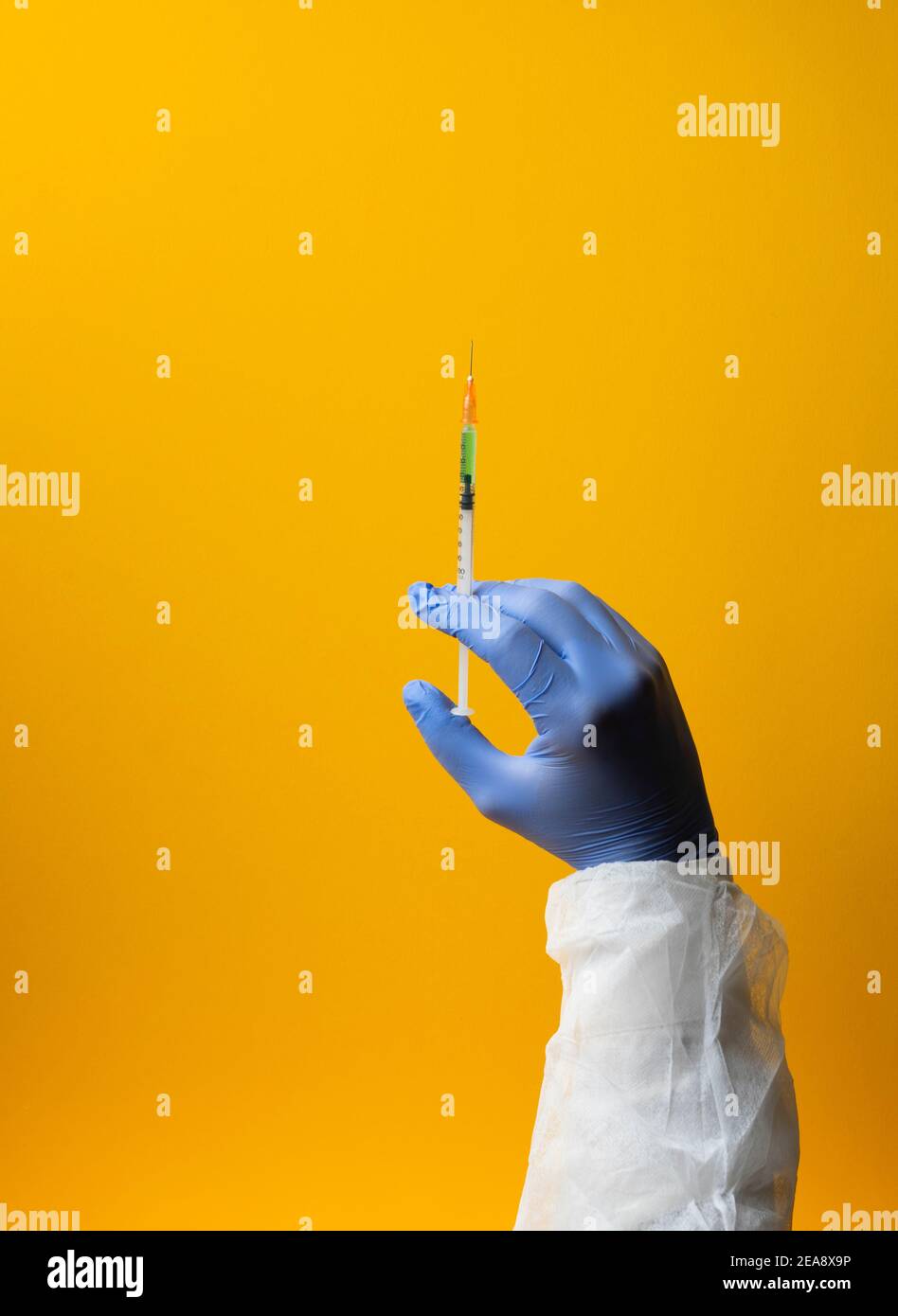 Laboratorio mano in guanti medici trattamento vaccino ricerca su sfondo giallo. Immagine verticale Foto Stock