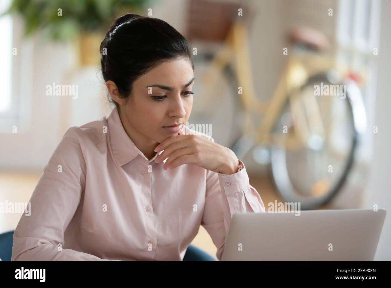 Seria giovane donna indiana che lavora al computer a casa Foto Stock