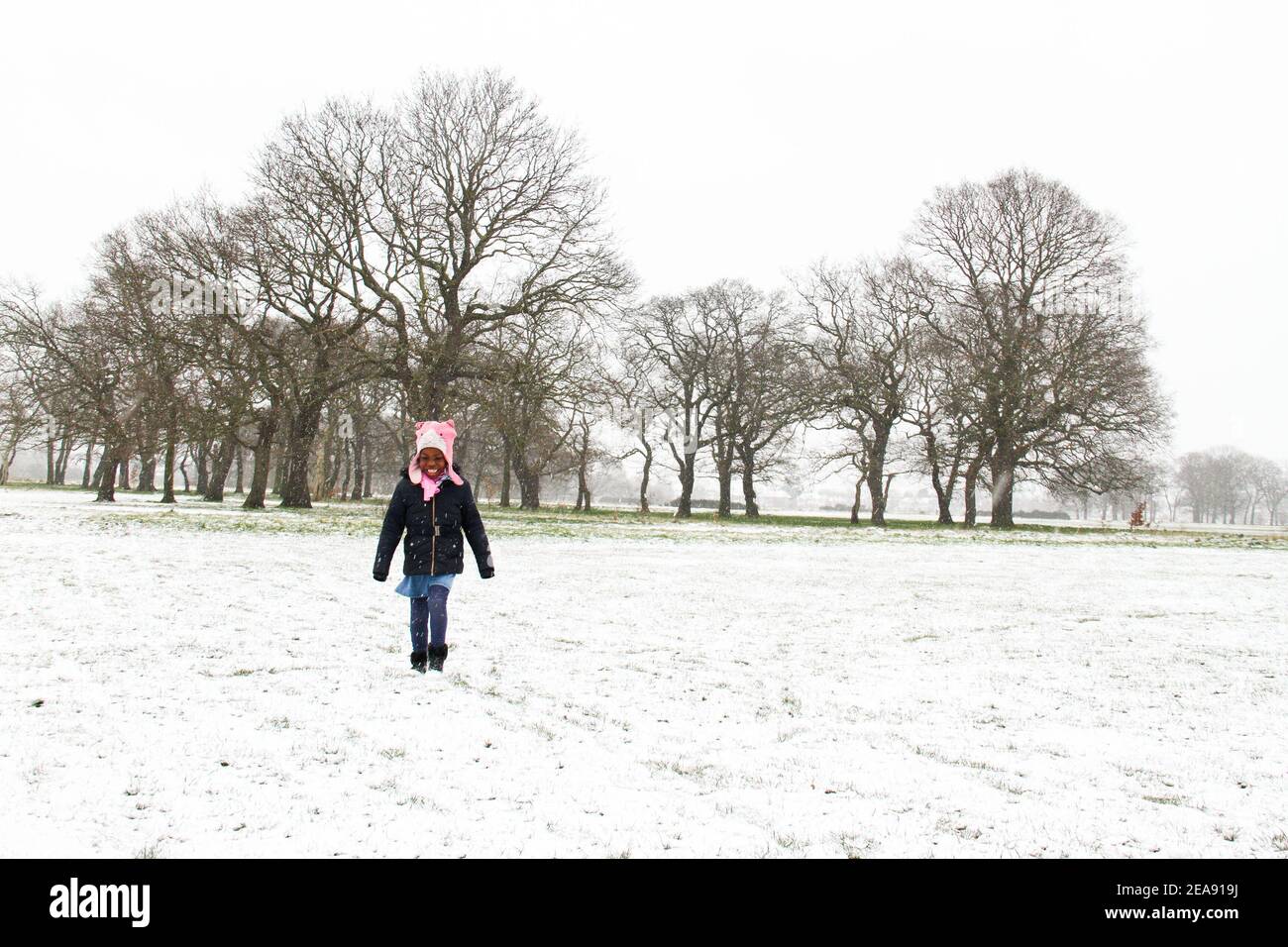 Una giovane ragazza cammina lungo un Wanstead Park innevato. La neve e il ghiaccio pesanti hanno portato disagi in alcune parti del Regno Unito, con Londra che riceve circa 5 cm di neve. I forti venti orientali di Storm Darcy hanno precipitato le temperature in alcune parti del Regno Unito a meno di uno. Foto Stock