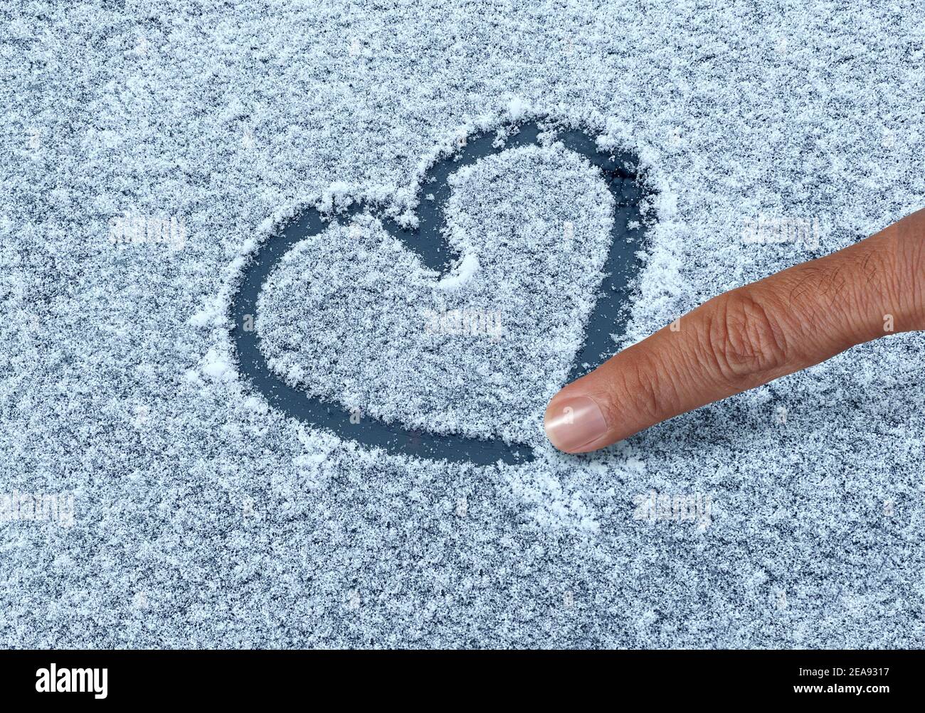 Disegnare un cuore di neve con un dito come un divertente simbolo d'amore invernale come una forma romantica saluti valentine su una superficie ghiacciata tempo. Foto Stock