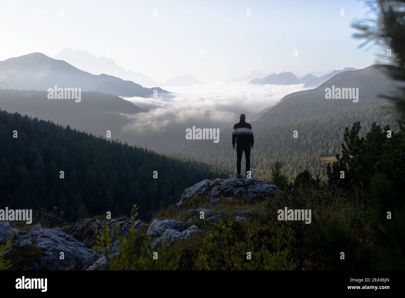 Escursionisti sulla roccia prima dell'alba alle cinque Torri nelle Dolomiti, Alto Adige, Italia. Nella valle si trova un mare di nebbia, sul quale si estendono diverse catene montuose Foto Stock