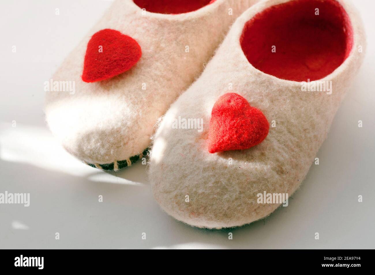 pantofole in feltrato fatte a mano con decorazioni a cuore rosso sui fari solari Foto Stock