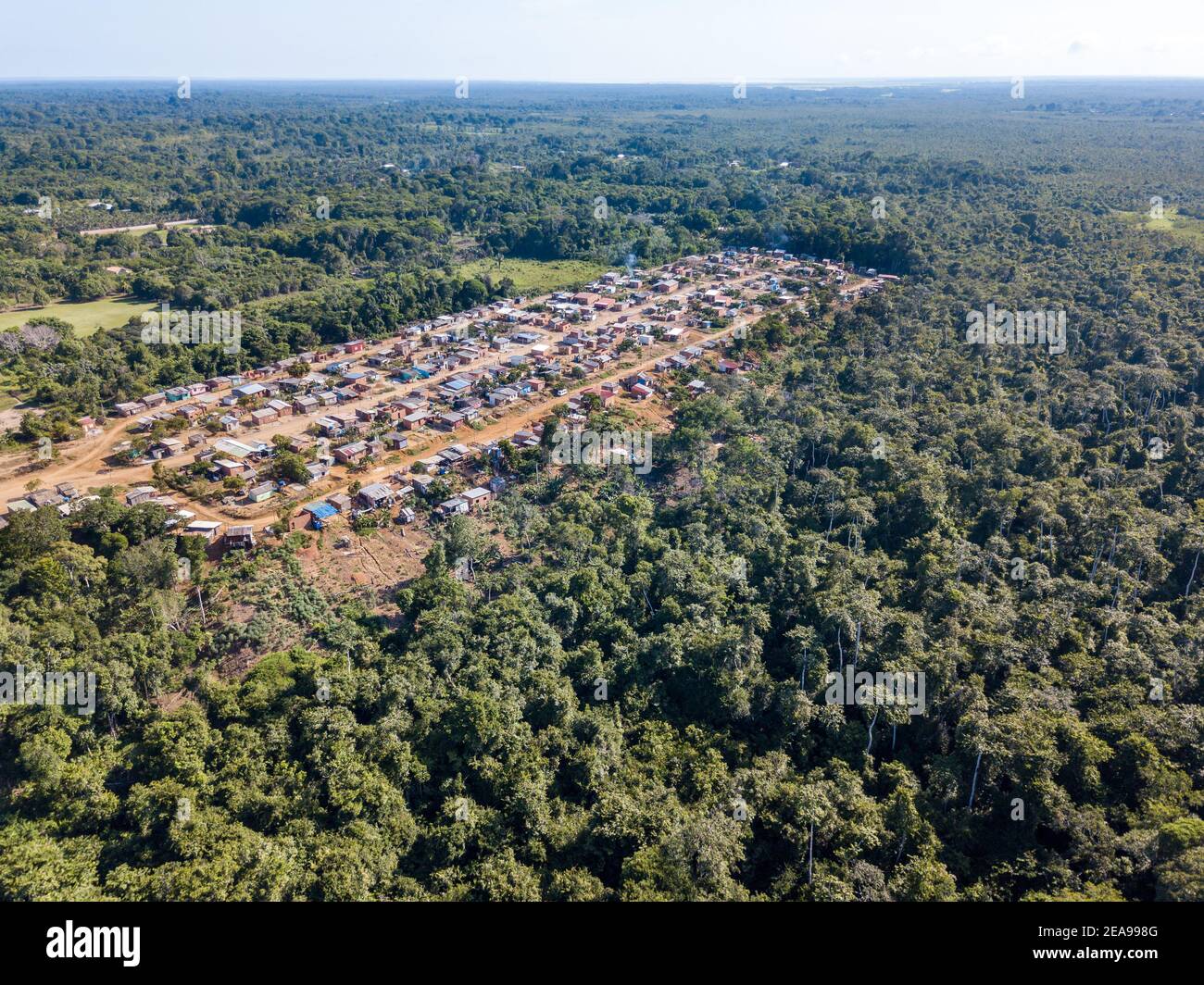 Vista aerea di case costruite villaggio e alberi di foresta nella zona di deforestazione nella foresta amazzonica, Brasile. Concetto di ambiente, ecologia, globale. Foto Stock