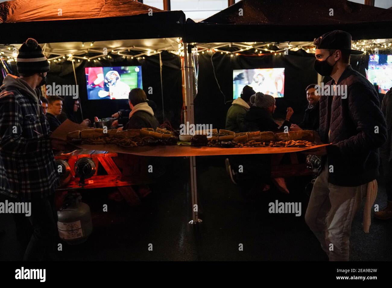 Philadelphia, Stati Uniti. 7 Feb 2021. Una cheesesteak Philly lunga cinque piedi viene portata a un tavolo da pranzo all'aperto al Tradeesman's, un bar e ristorante, con Super Bowl LV che gioca alla televisione a Philadelphia, USA. Credit: Chase Sutton/Alamy Live News Foto Stock