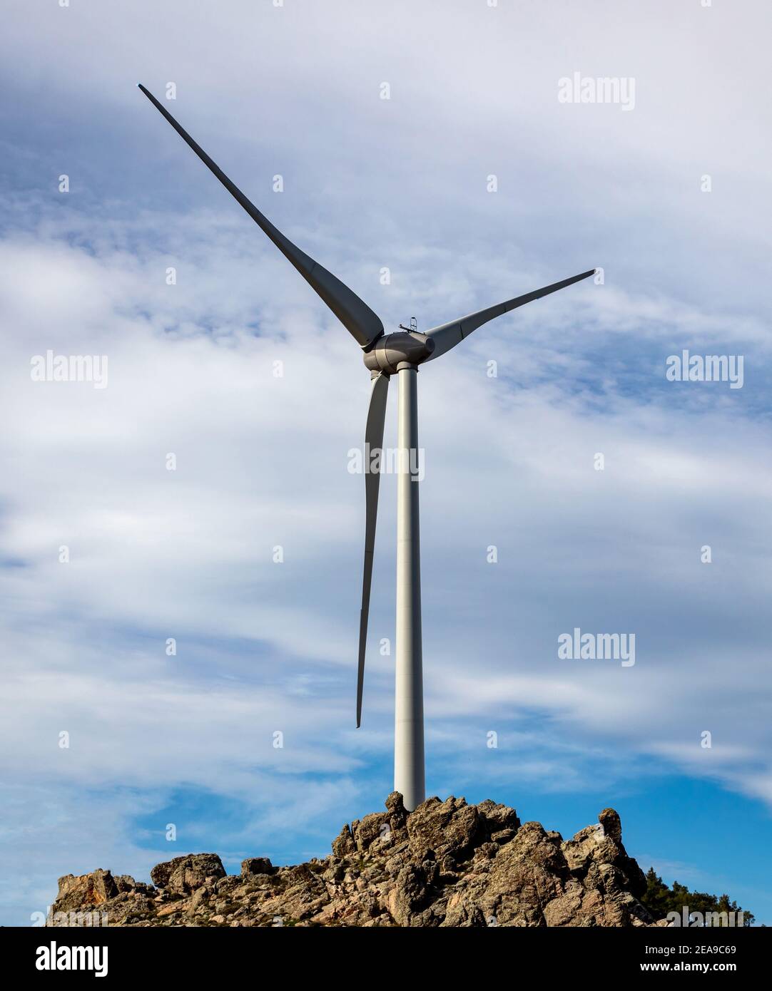 Turbina eolica sulla cima della collina rocciosa, vista aerea del drone, generazione di energia alternativa, cielo blu nuvoloso, verde eco-industria rinnovabile Foto Stock