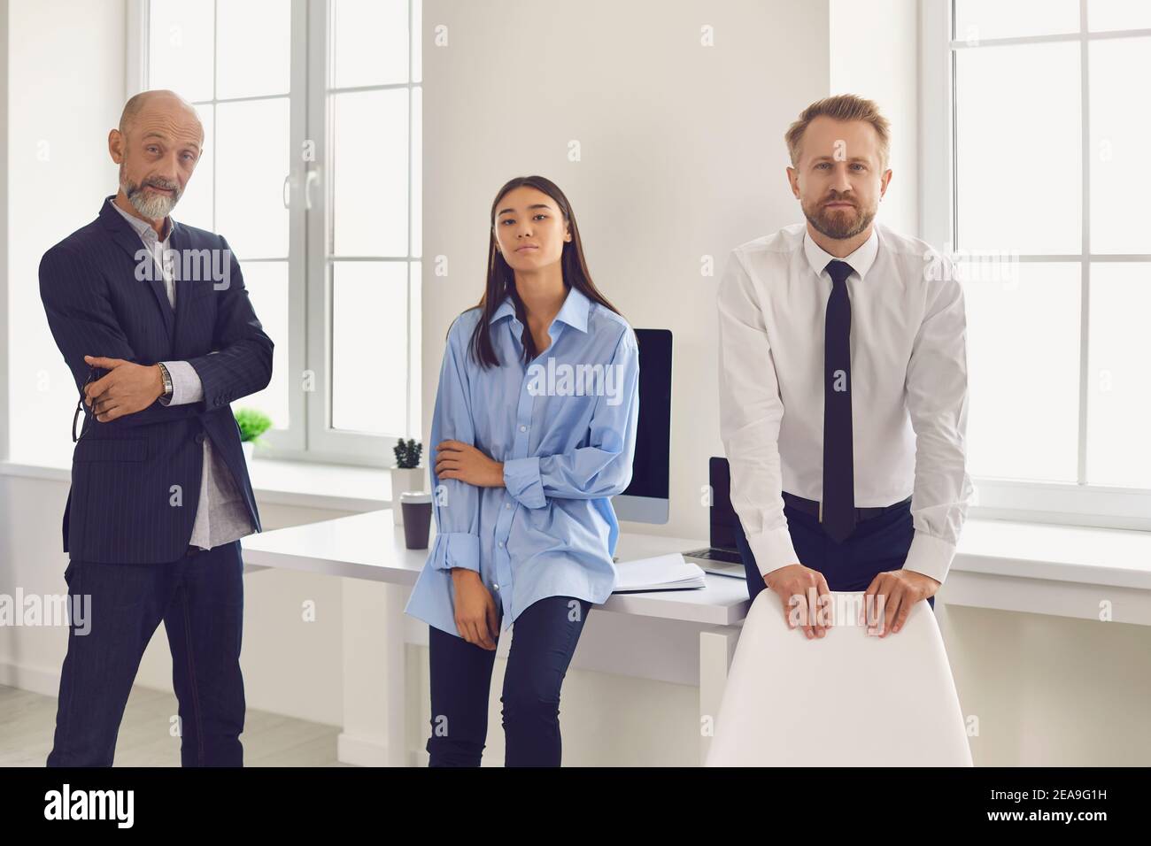 Gruppo di colleghi che guardano la fotocamera in ufficio durante l'avvio o la discussione sul progetto Foto Stock