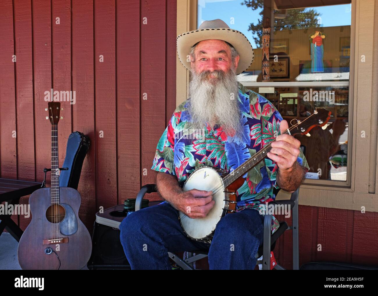 Un anziano musicista sceglie un banjo a quattro corde e serenata i visitatori di fronte a un negozio di curio a Sisters, Oregon. Foto Stock