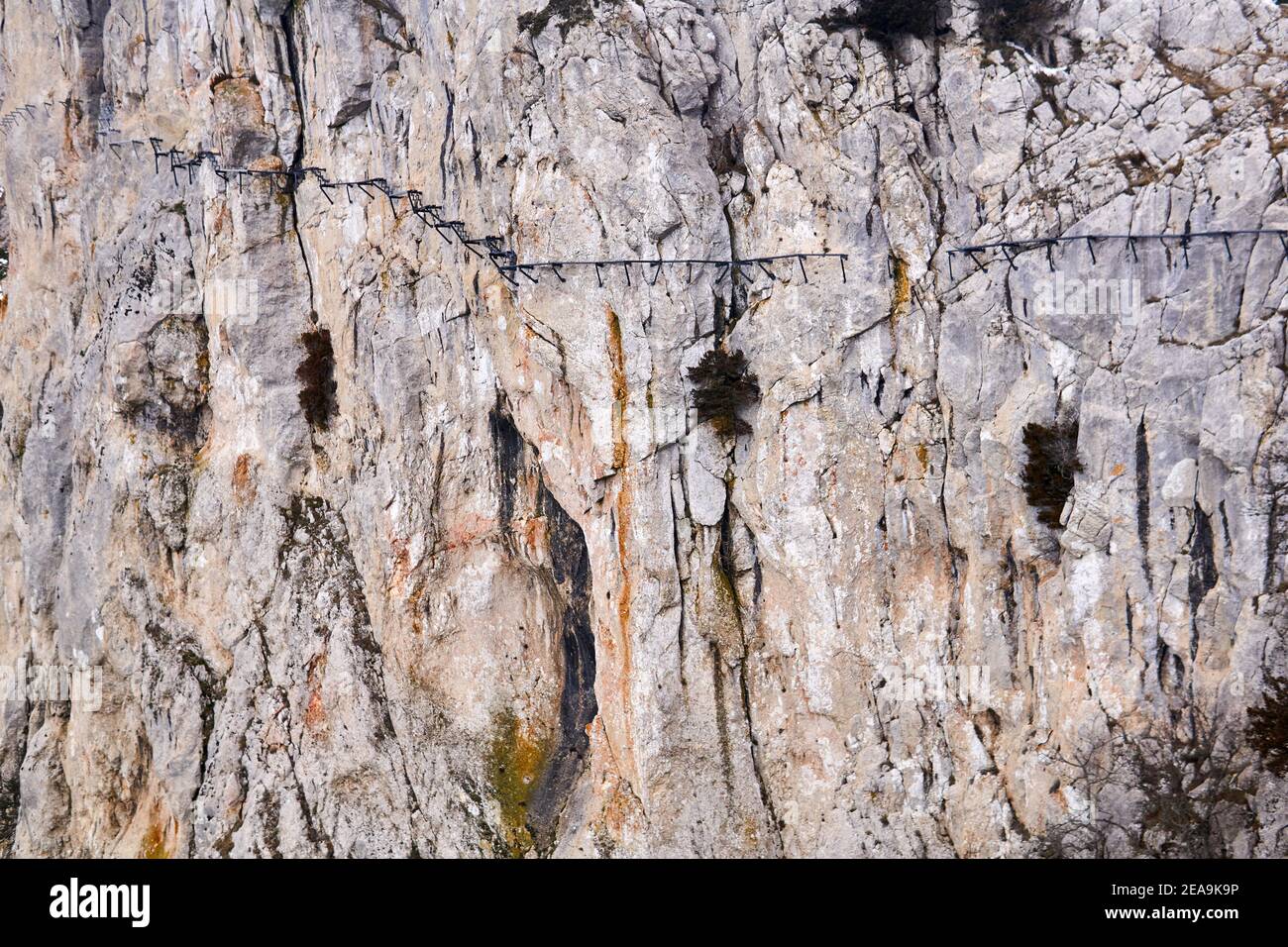 sfondo - la superficie di una roccia verticale enorme con un percorso sospeso distrutto su di esso Foto Stock