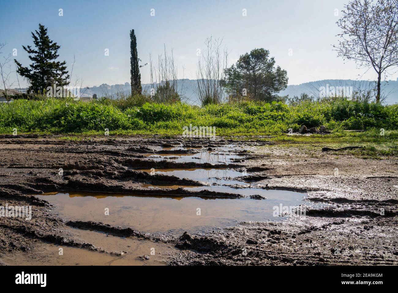 Una strada fangosa con pozze d'acqua piovana, in una giornata limpida e soleggiata, vicino a Gerusalemme, Israele Foto Stock