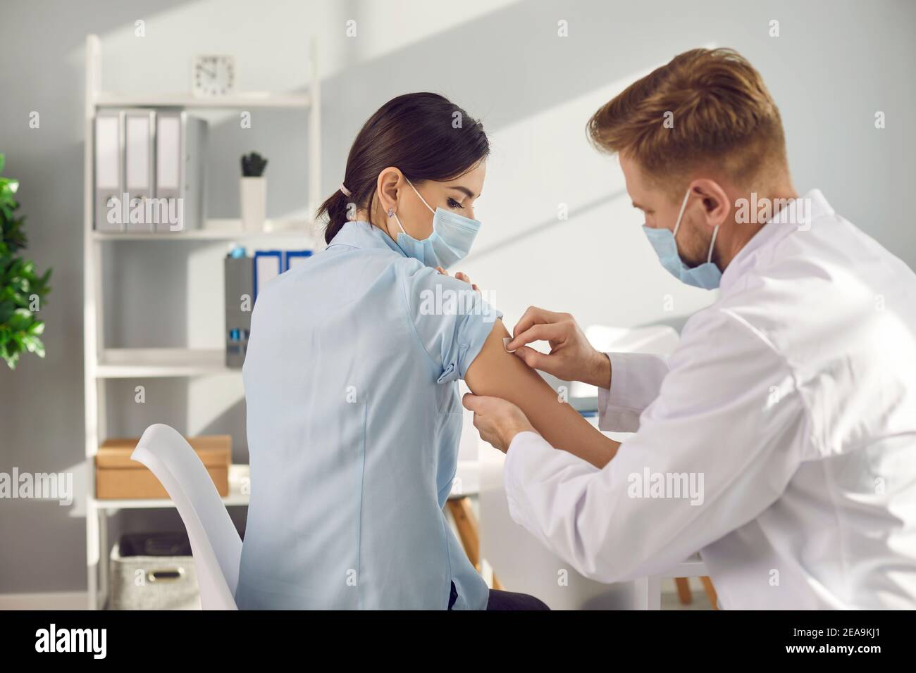 Uomo medico lavoratore attaccando gesso medico al braccio pazienti donna dopo la vaccinazione Foto Stock