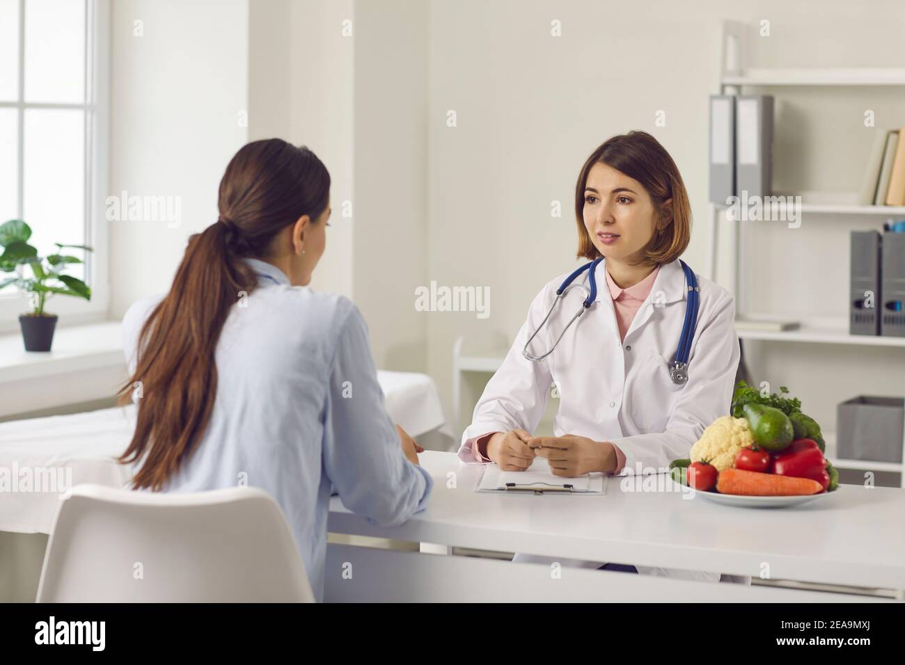 Nutrizionista che parla con la giovane donna di problemi di salute e di fare programma dietetico individuale Foto Stock