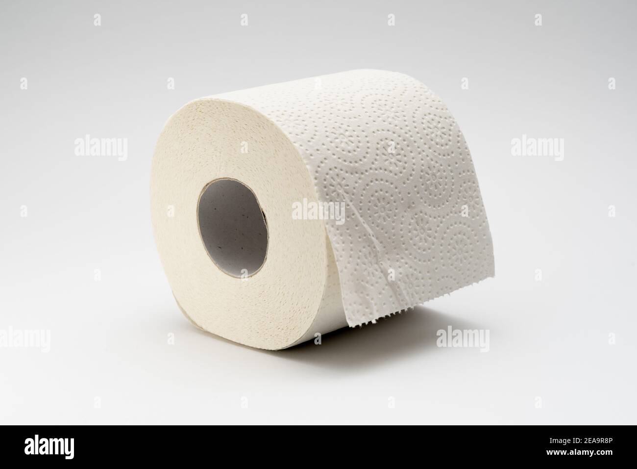 Rotolo bianco di carta igienica su sfondo bianco neutro. Tessuto bagno pieno di materiale riciclato Foto Stock