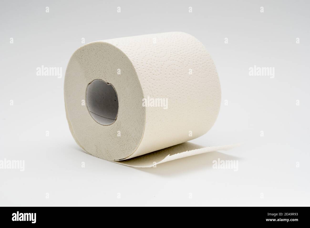 Rotolo bianco di carta igienica su sfondo bianco neutro. Tessuto bagno pieno di materiale riciclato Foto Stock