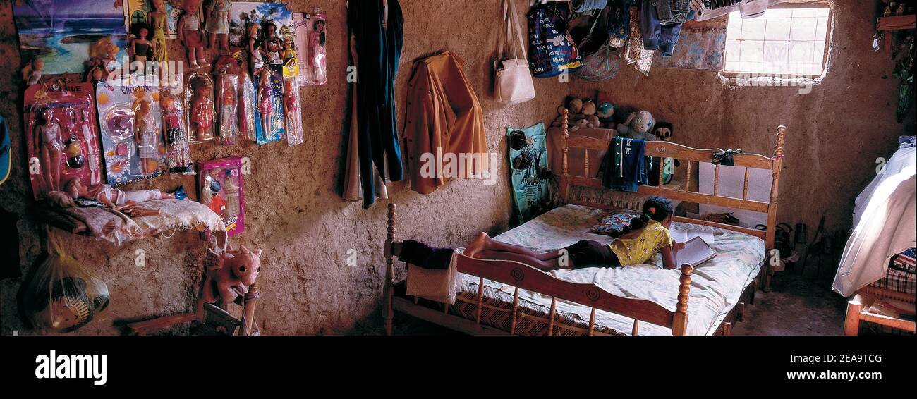 Bambino che impara sul suo letto in capanna semplice, in un povero distretto desertico del Venezuela; Sud America. Foto Stock
