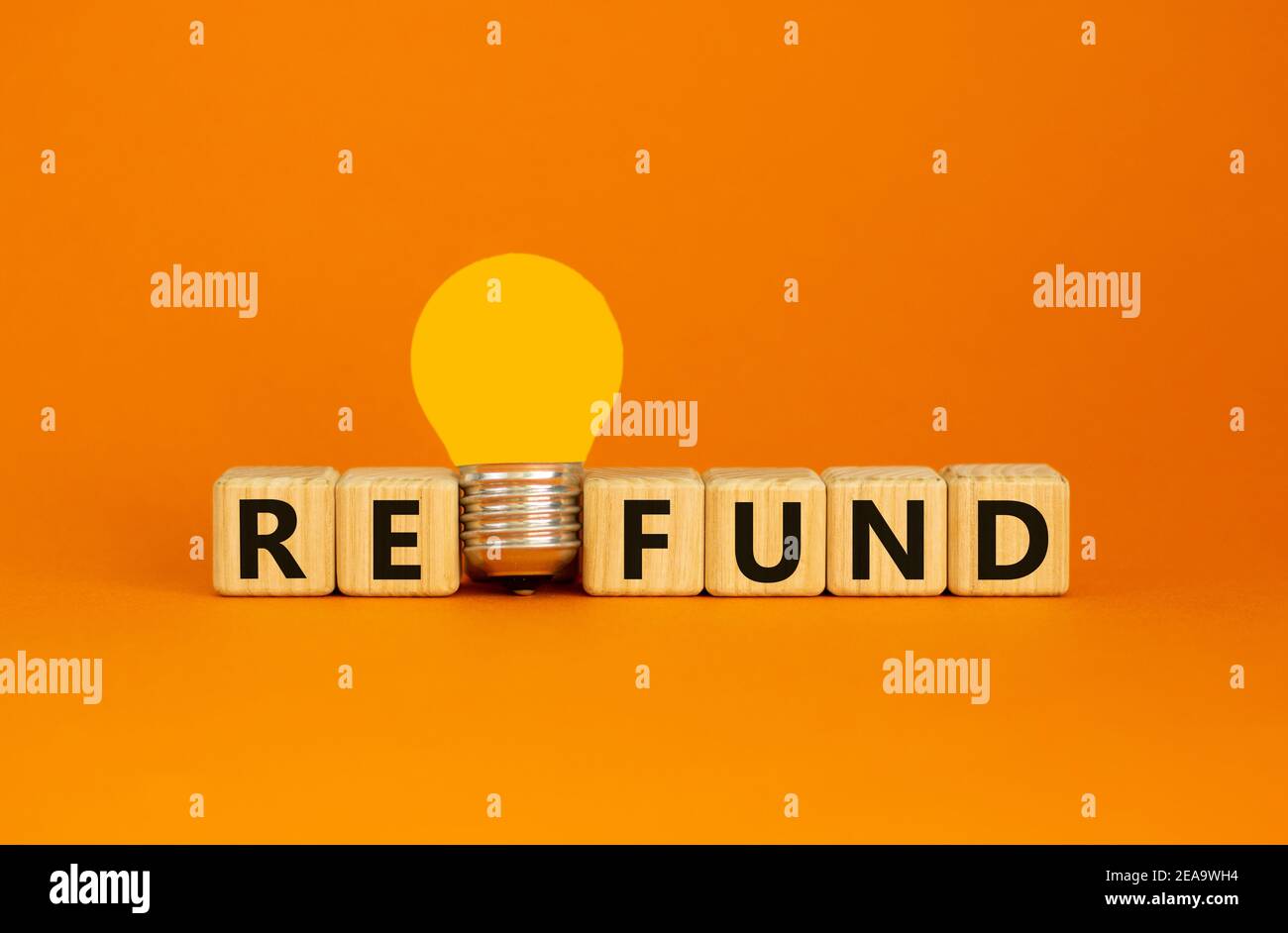Simbolo di rimborso. Cubetti di legno con la parola 'fondo'. Lampadina gialla. Bellissimo sfondo arancione. Business e concetto di rimborso. Spazio di copia. Foto Stock