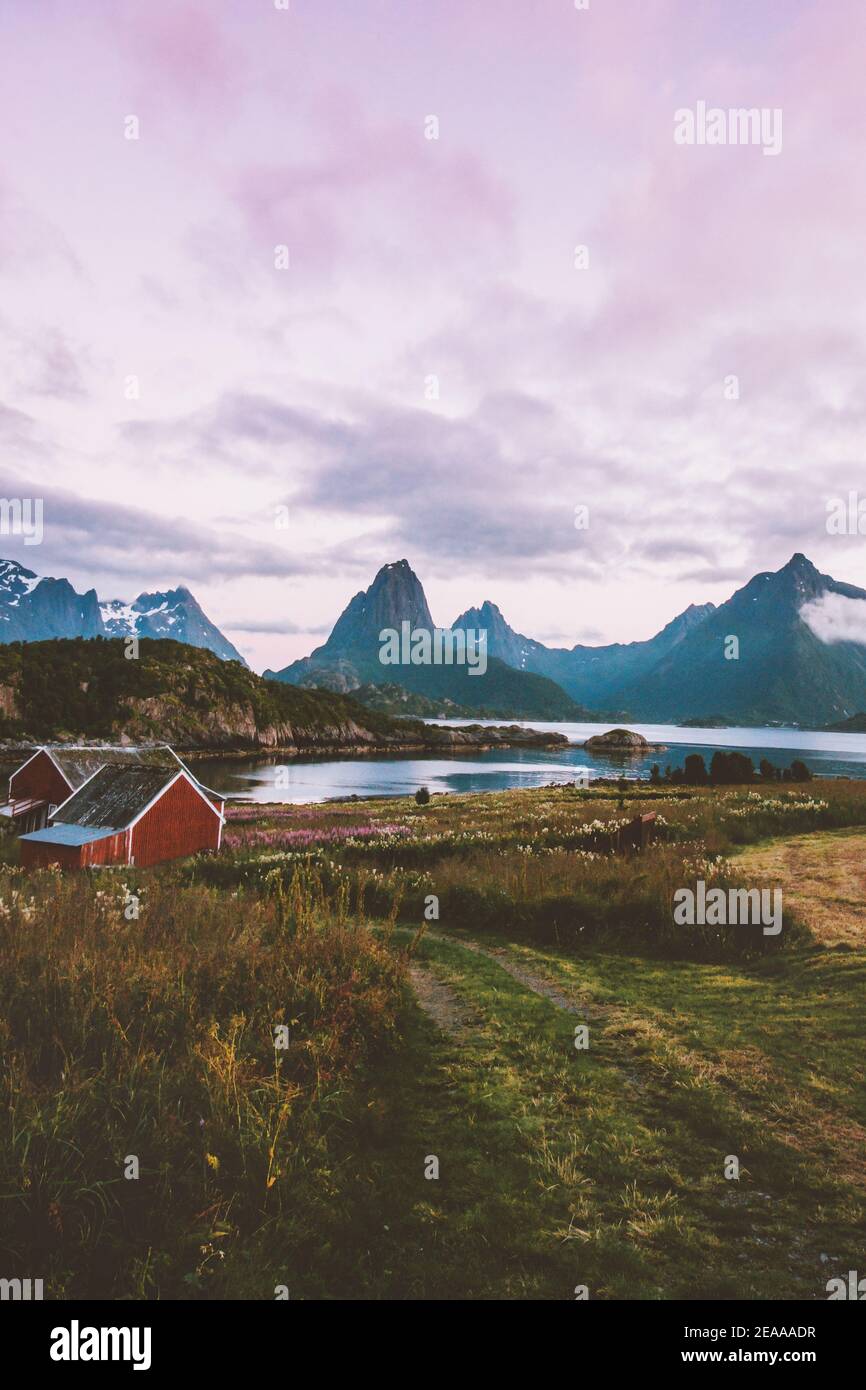 Villaggio tradizionale in Norvegia tramonto paesaggio montagne sopra fiordo e. Casa rossa campagna nelle isole Lofoten rurale scandinavo viaggio natura bea Foto Stock