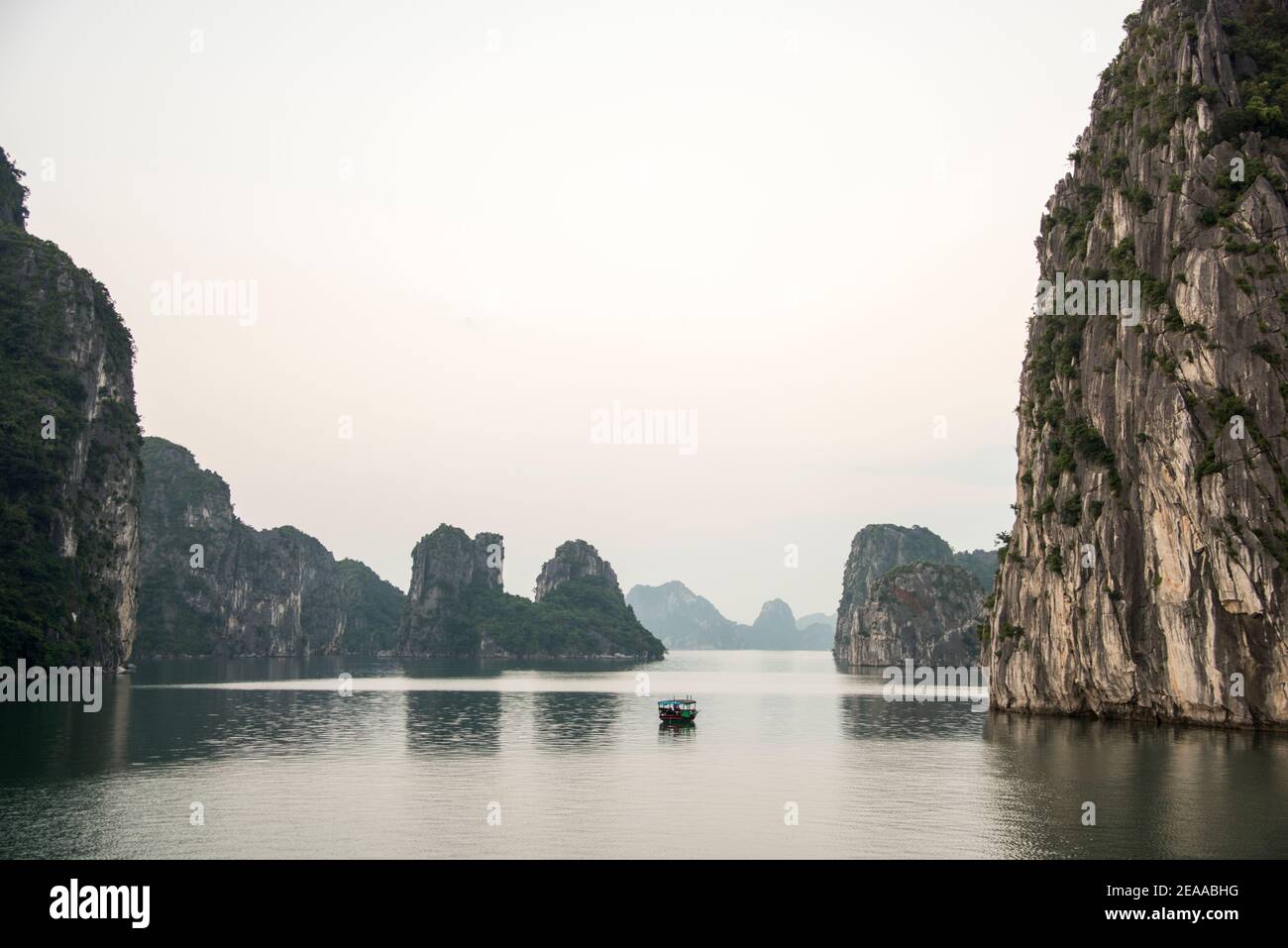 Barca da pesca tra le rocce, Halong Bay, Vietnam Foto Stock