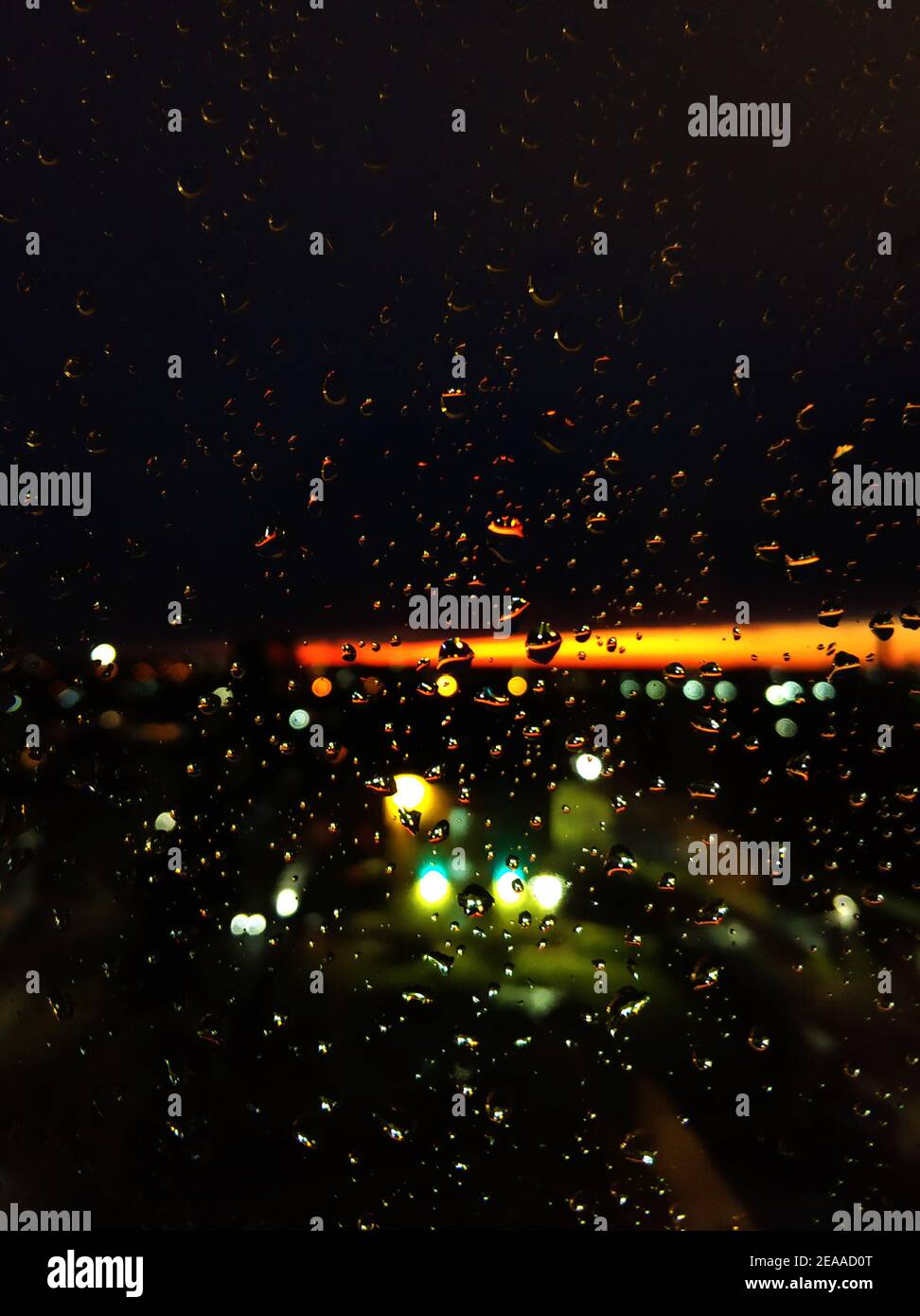 Gocce di pioggia su vetro. Livin durante il tramonto. Cielo notturno con una striscia arancione brillante. Foto Stock