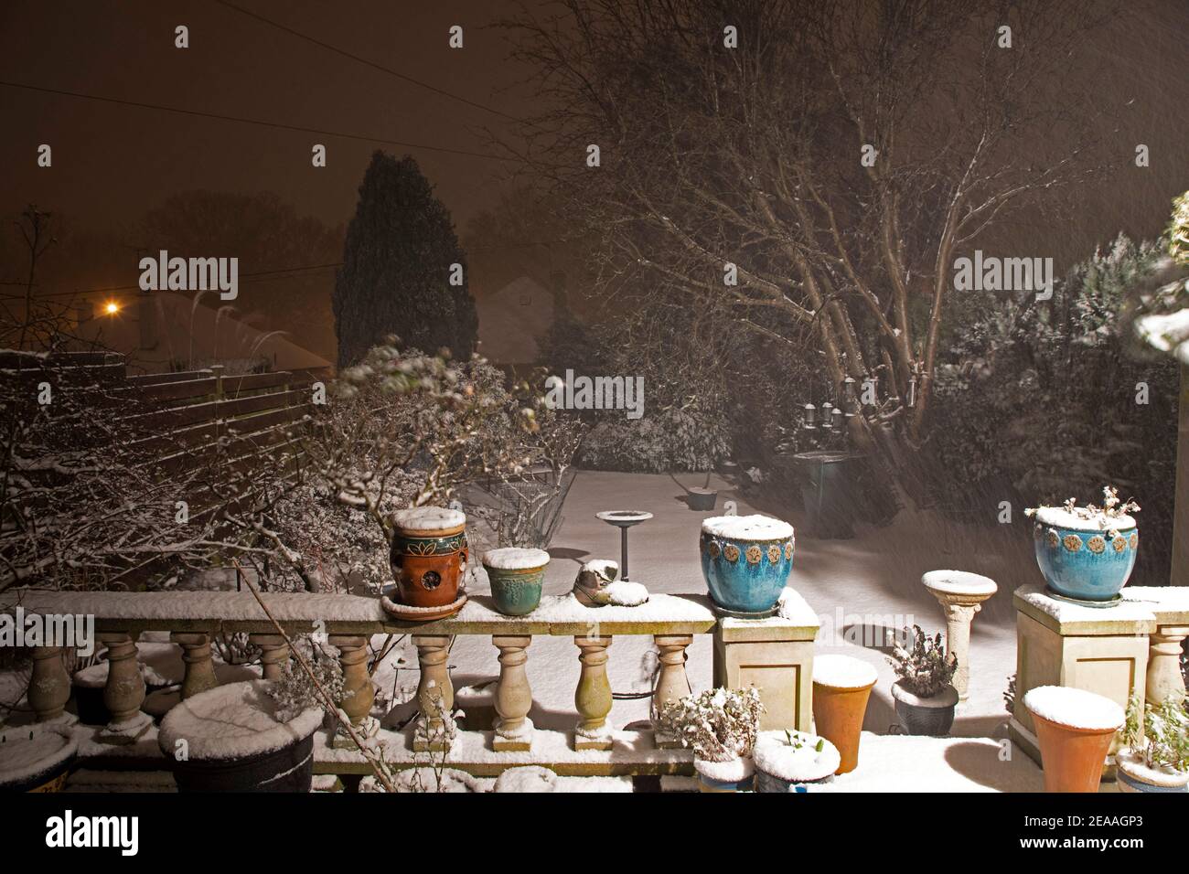 Edimburgo, Scozia, Regno Unito. 8 febbraio 2021. Neve pesante che cade a est della città, con più attesa di notte e verso domani. Nella foto: Giardino posteriore con ringhiera e vasi di fiori con illuminazione di sicurezza. Foto Stock