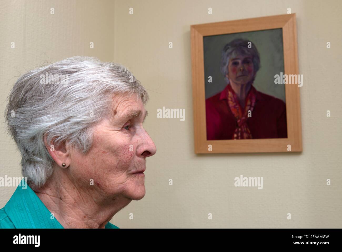 Anziana signora seduta accanto ad un ritratto dipinto di se stessa Foto Stock