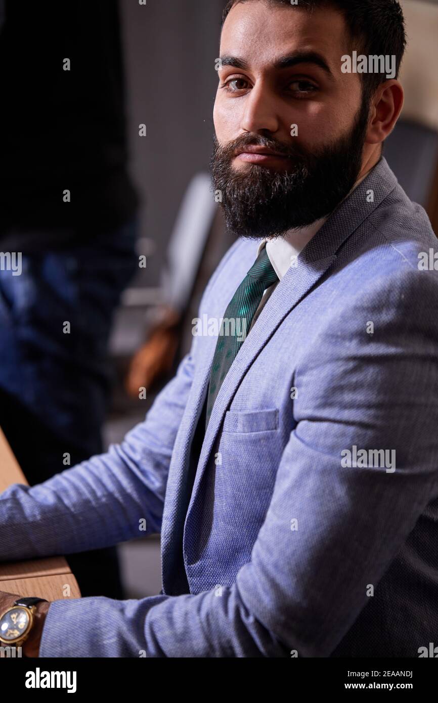 bruna sicura bearded esecutivo in tuta che posa alla macchina fotografica guardando seriamente, concetto di gente di affari Foto Stock