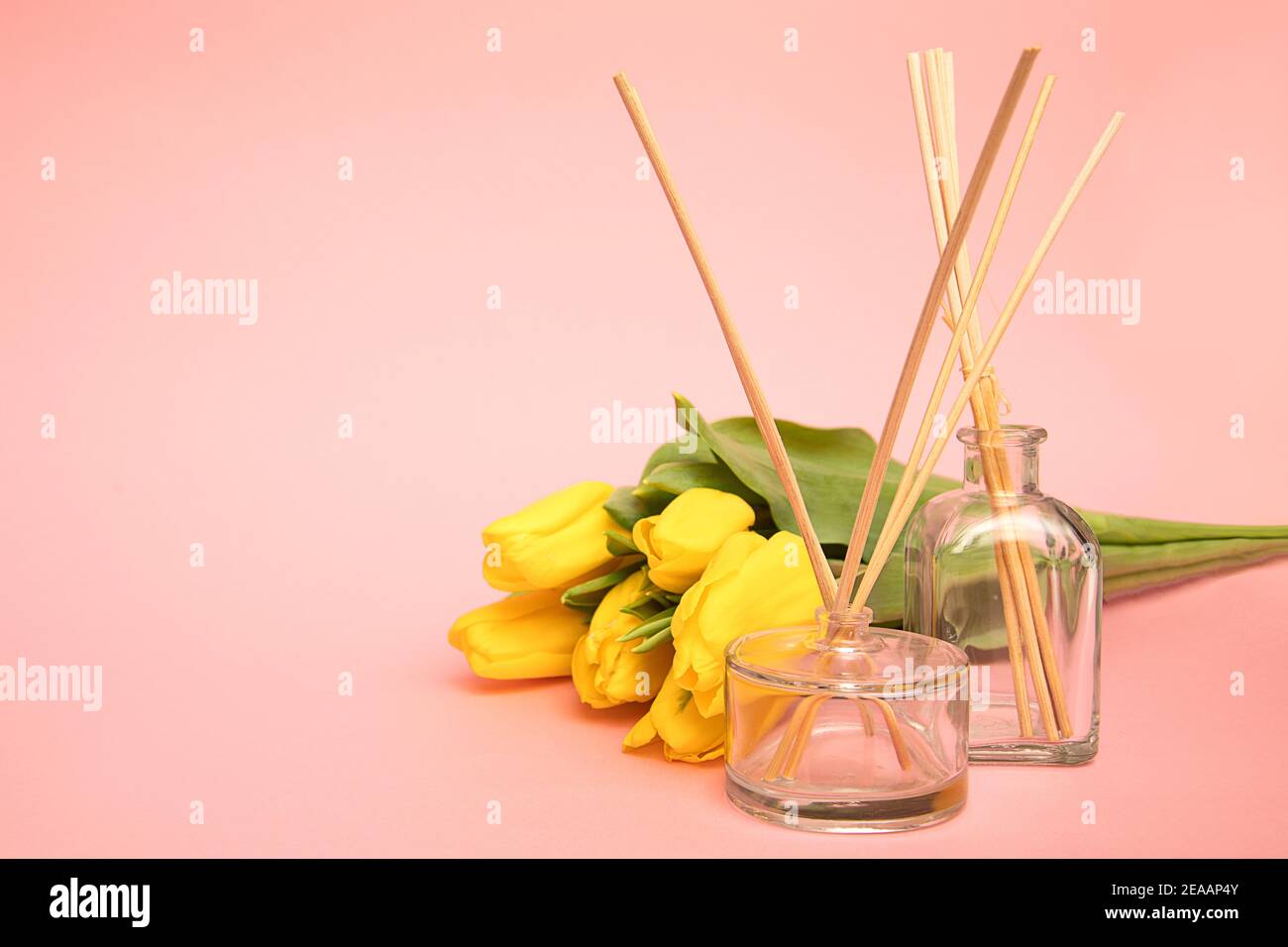 Deodorante per ambienti con bastoncini di aroma in legno e fiori di tulipano su sfondo rosa con spazio per la copia. Concetto di aria fresca a casa Foto Stock