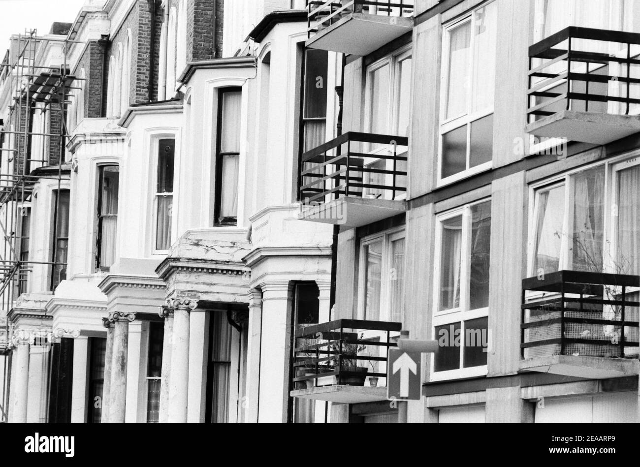 UK, West London, Notting Hill, 1973. Rundown e faticosamente grandi case a quattro piani stanno iniziando ad essere restaurate e ridecorate. Vicino a No:2 Powis Gardens. A destra si trovano i garage di Powis Court, sotto i balconi, ingresso in Powis Square. Foto Stock