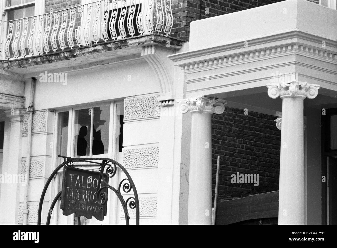 UK, West London, Notting Hill, 1973. Rundown e faticosamente grandi case a quattro piani stanno iniziando ad essere restaurate e ridecorate. Vetro della finestra rotto nella casa (n° 9 o 10) vicino al Talbot Tabernacle lato ingresso in Powis Gardens. Foto Stock