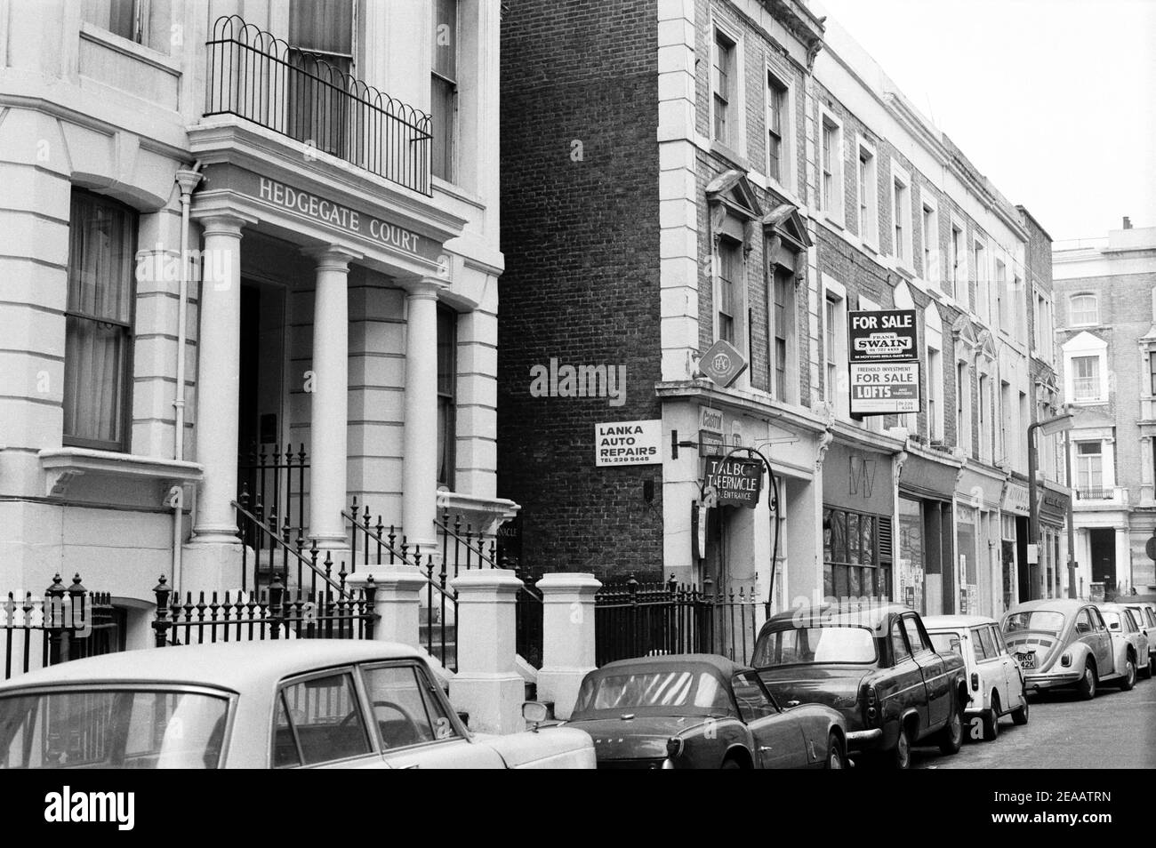 UK, West London, Notting Hill, 1973. Rundown e faticosamente grandi case a quattro piani stanno iniziando ad essere restaurate e ridecorate. 14-16 Powis Terrace, Hedgegate Court, con un ingresso laterale al Talbot Tabernacle. Firma di Freehold Investment for sale. Foto Stock