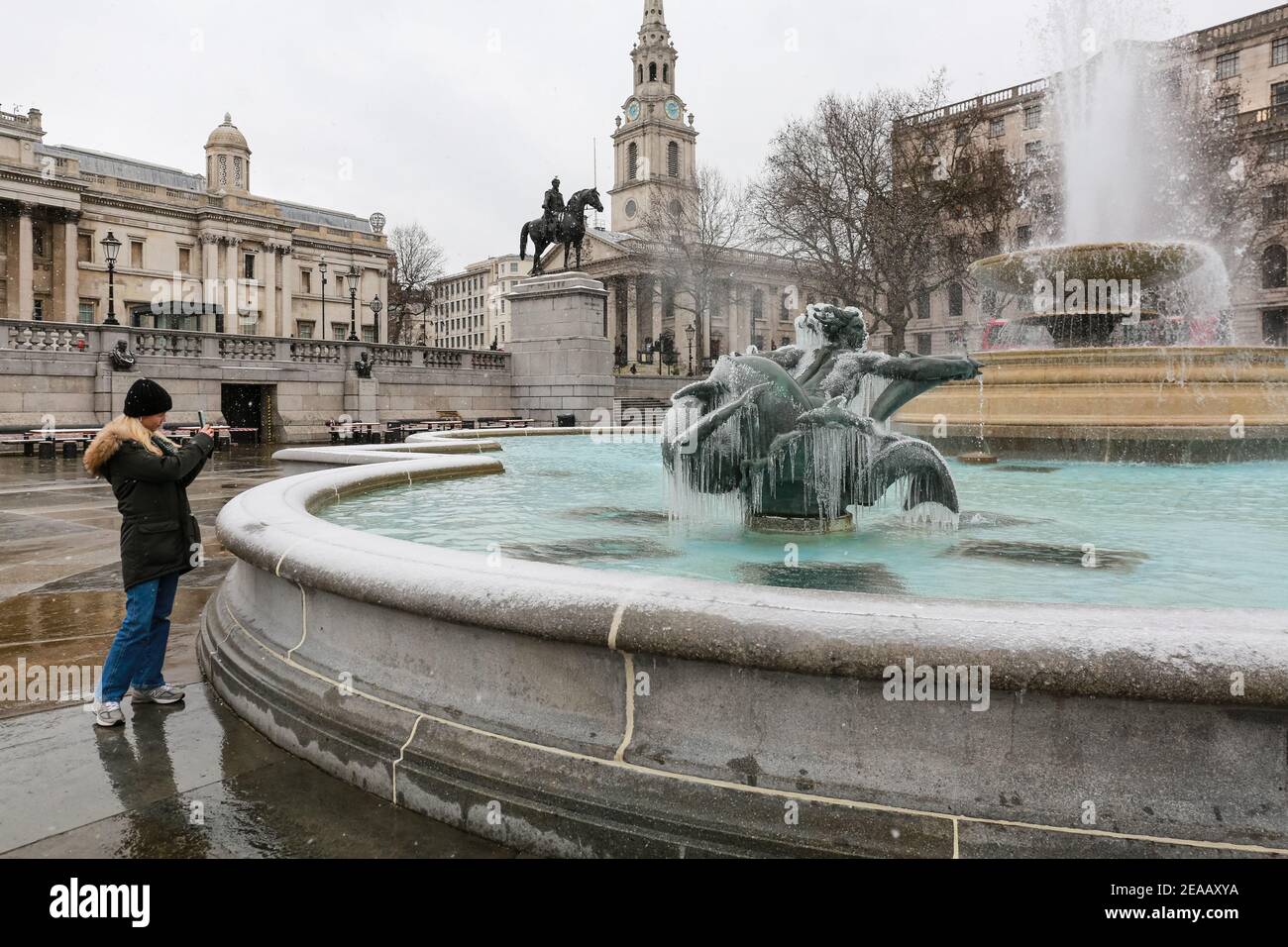 Londra, Regno Unito. 08 Feb 2021. Regno Unito Meteo: Una donna scatta una foto di una statua ricoperta di ghiaccio in una fontana in Trafalgar Square. Credito: Waldemar Sikora Foto Stock