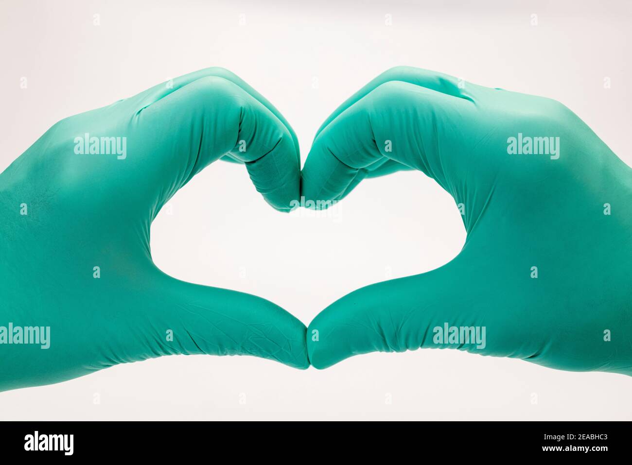 Le mani del medico che fanno il segno del cuore, dettaglio, forma del cuore, guanti verdi monouso, Foto Stock